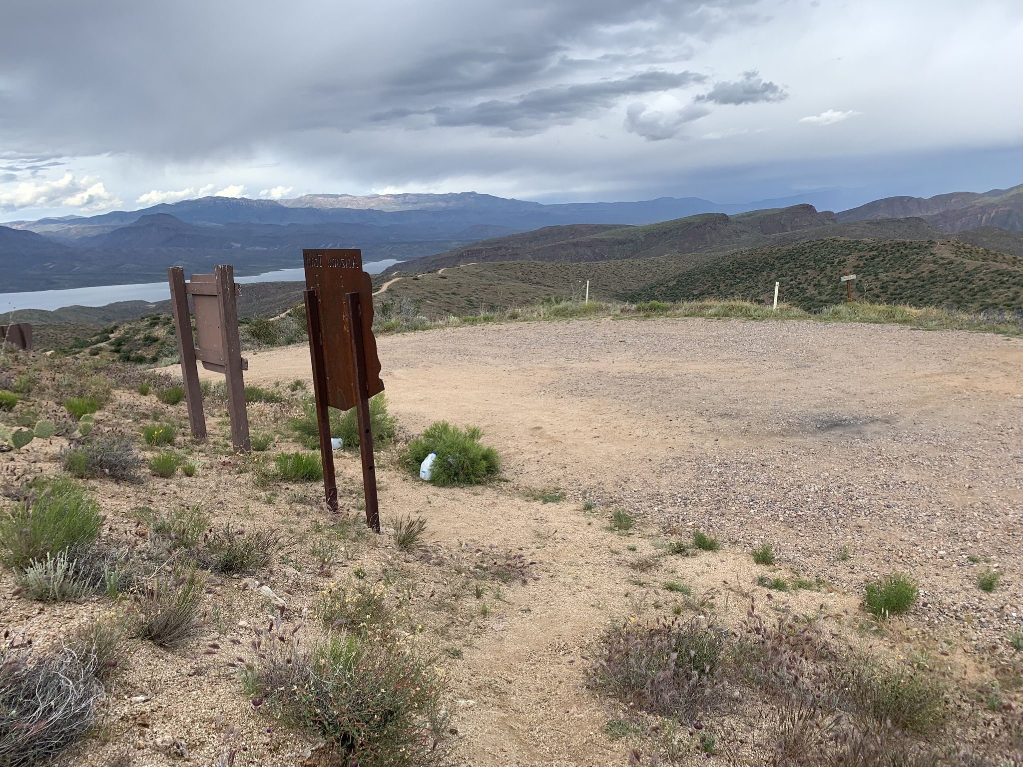 Dirt clearing with signs overlooking a distant lake under cloudy skies. - Browns Peak via Four Peaks Trail #130