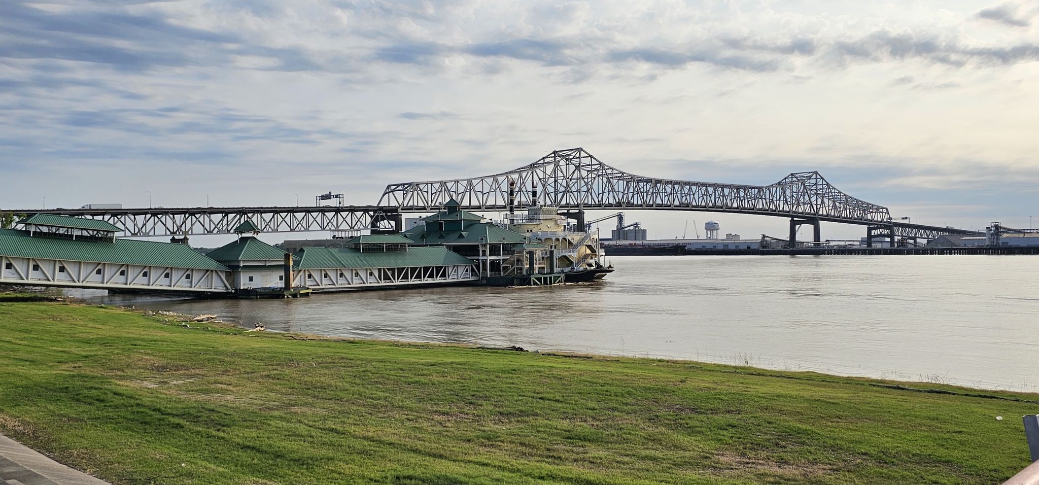 Large metal bridge over a wide river with a paddlewheel boat docked. - City-Brooks Community Park – USS Kidd Veterans Museum loop from Louisiana State University