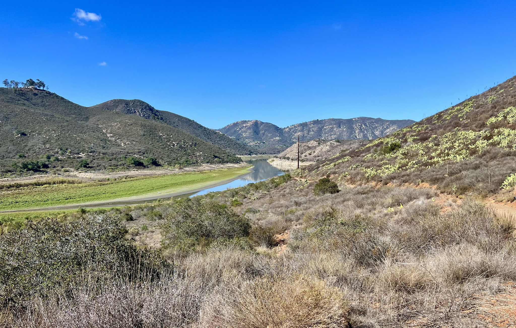 A narrow river winds through a wide valley with green and arid hills. - Lake Hodges – Lake Hodges Trail loop from Westfield North County