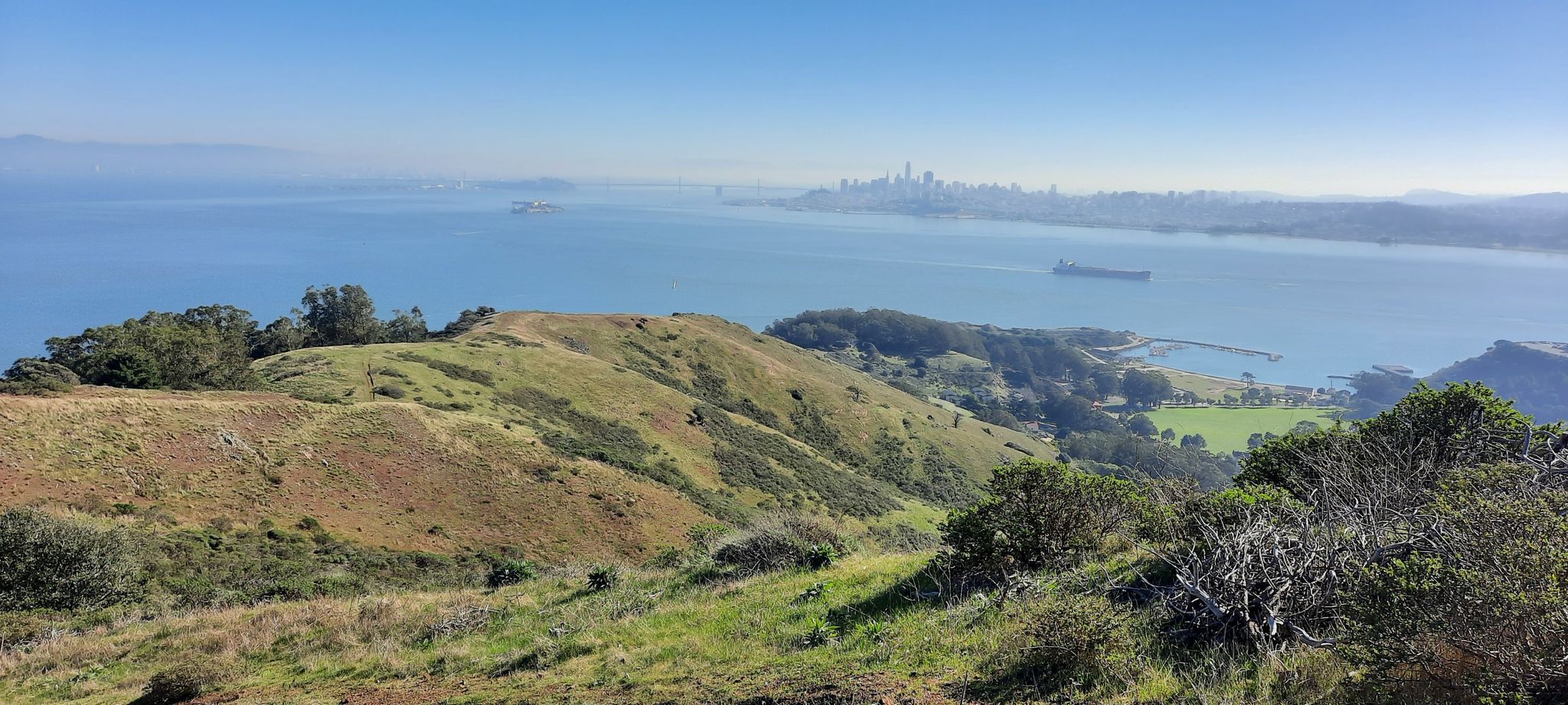Hilly landscape overlooking a bay with a distant city skyline. - SCA Trail to Engagement Hill