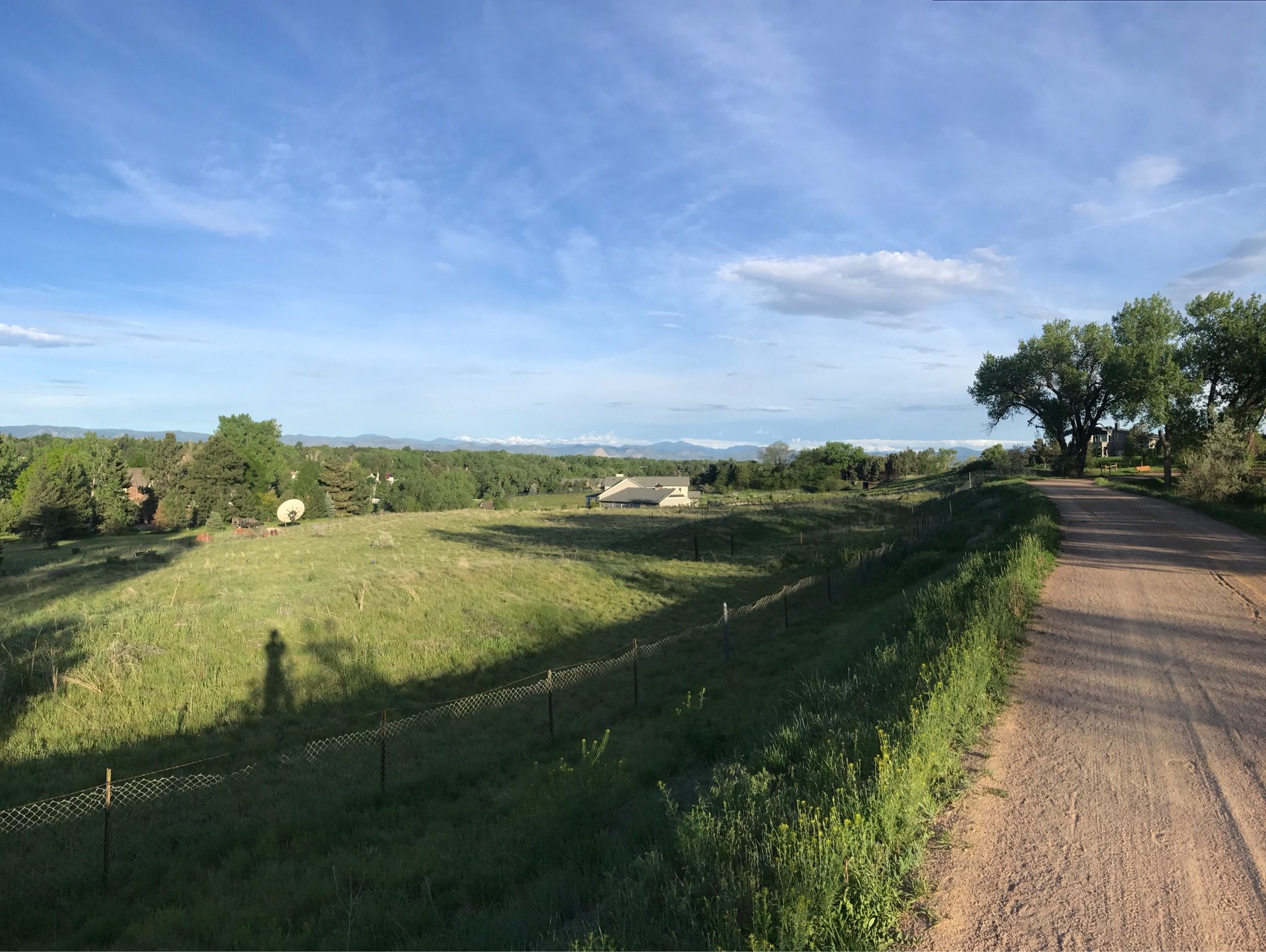 Sunny field with a dirt path, distant trees, and a person's shadow. - Blackmer Lake – Sumac Hill Farm viewpoint loop from Yale