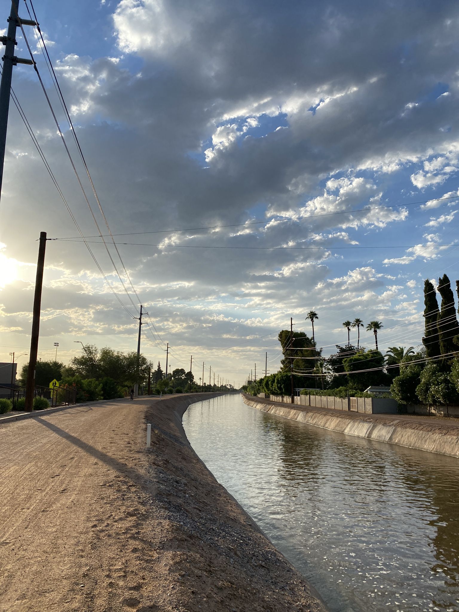A canal with a dirt path and power lines under a cloudy sunset sky. - Arizona Falls – Bike path along the canal loop from Echo Canyon Recreation Area