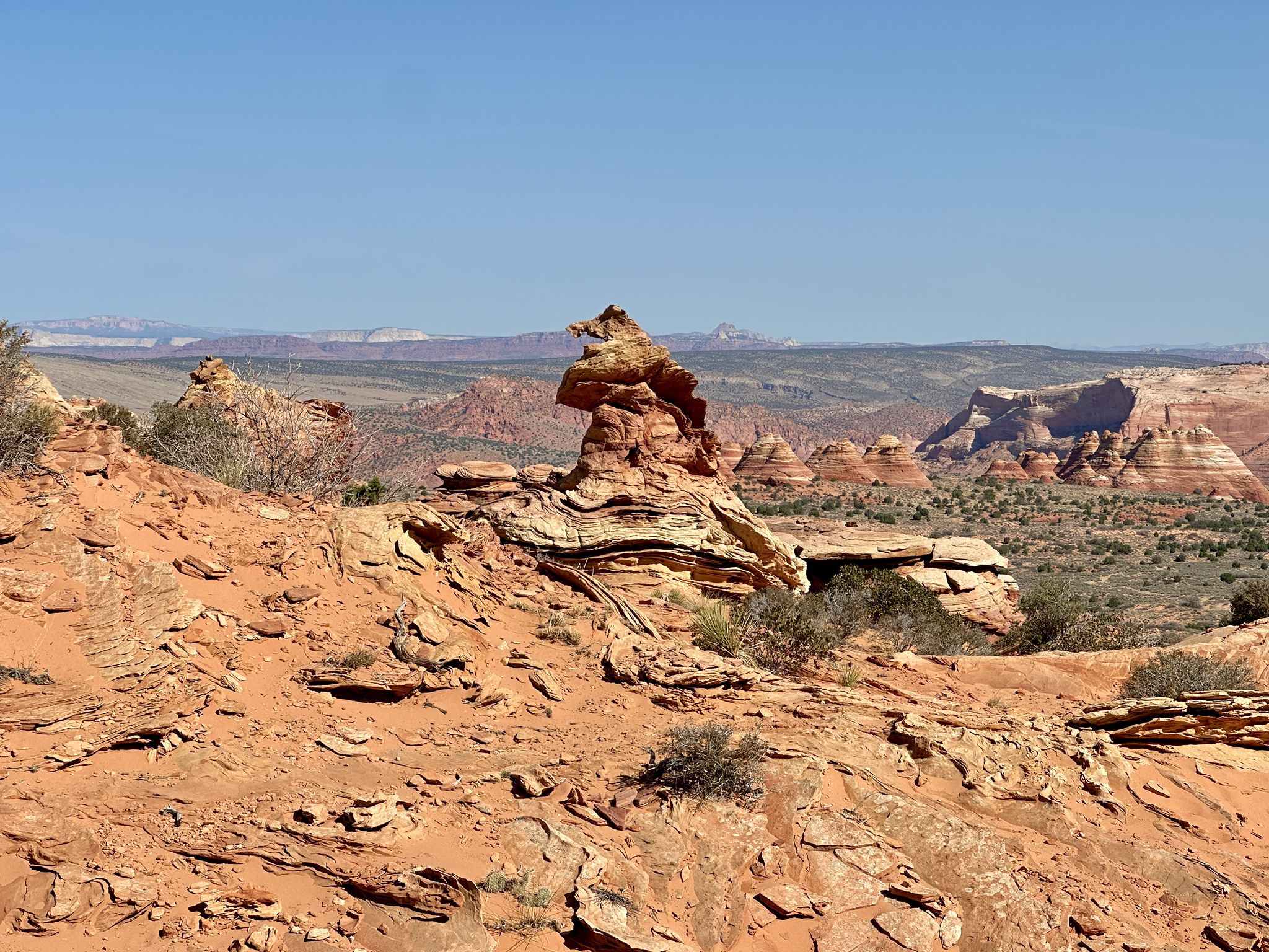 A unique rock formation stands prominently in a vast, sunny desert landscape. - Sunset Butte and Cottonwood Teepees Loop
