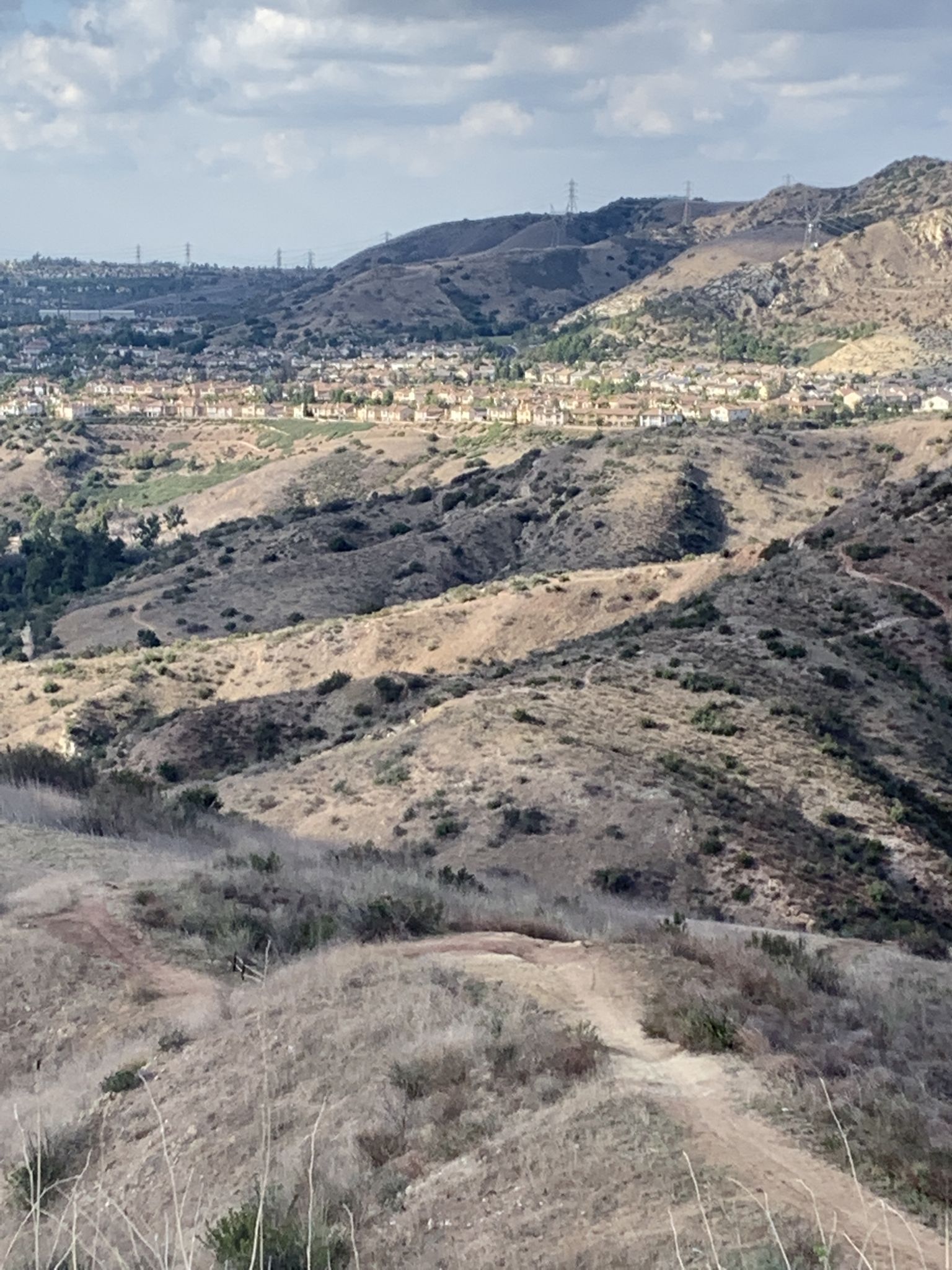 Dry, arid hills with a distant town under a partly cloudy sky. - Santiago Creek, Bobcat Meadow, Barham Ridge, and Coachwhip Loop