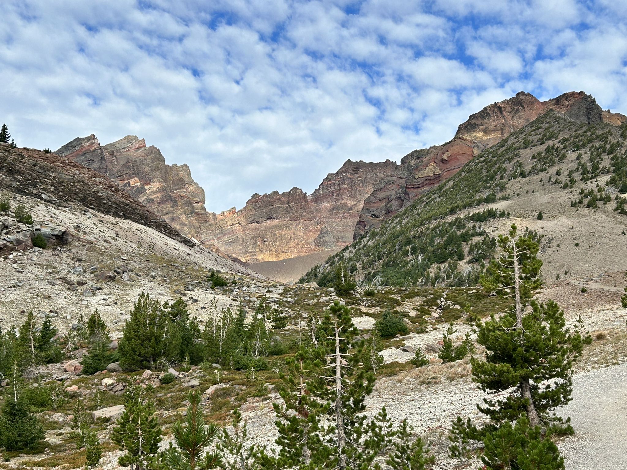 Valley with scattered trees leading to a dramatic rocky mountain range. - Broken Top Trail to No Name Lake