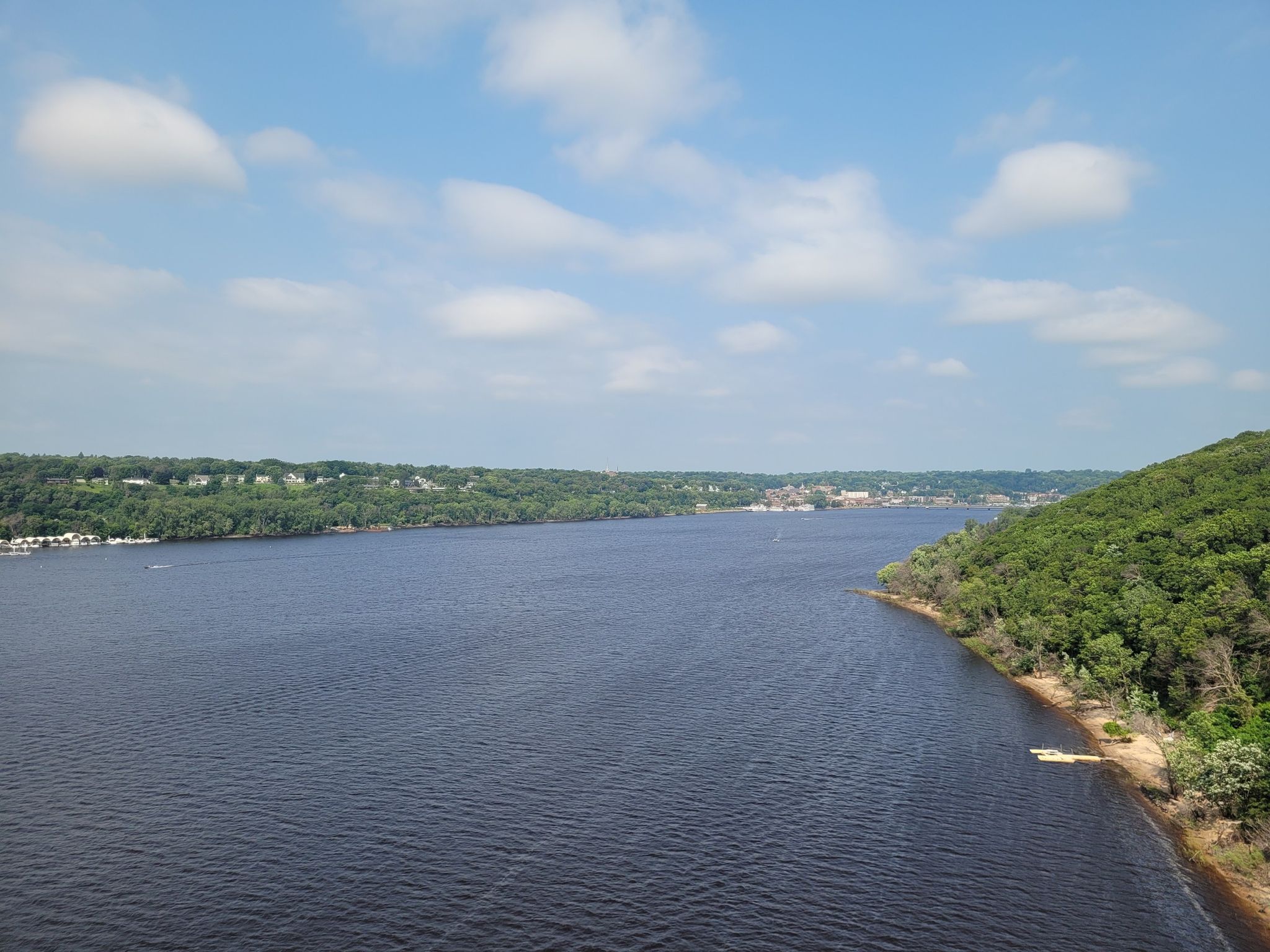 Wide river with forested banks under a blue sky with clouds. - Saint Croix Crossing Loop Trail