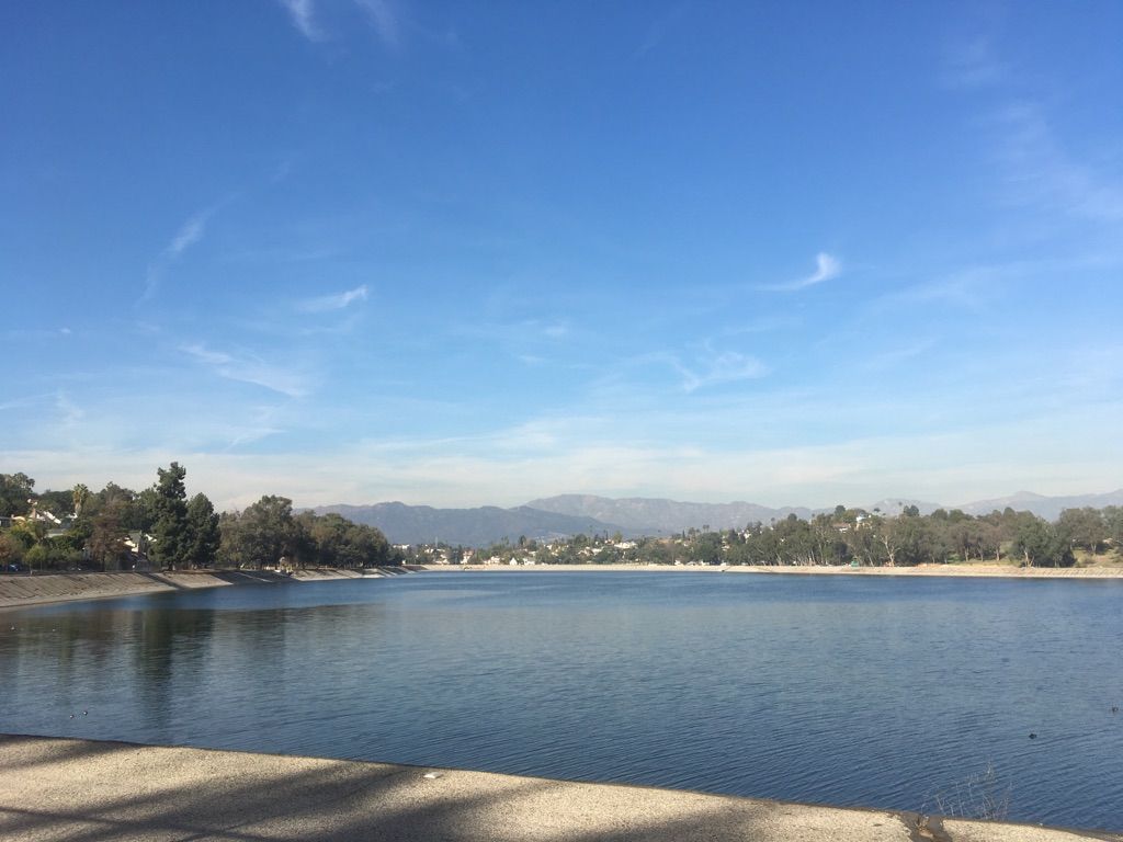 Vast blue lake with tree-lined shore and distant mountains under clear sky. - Silver Lake Reservoir Trail