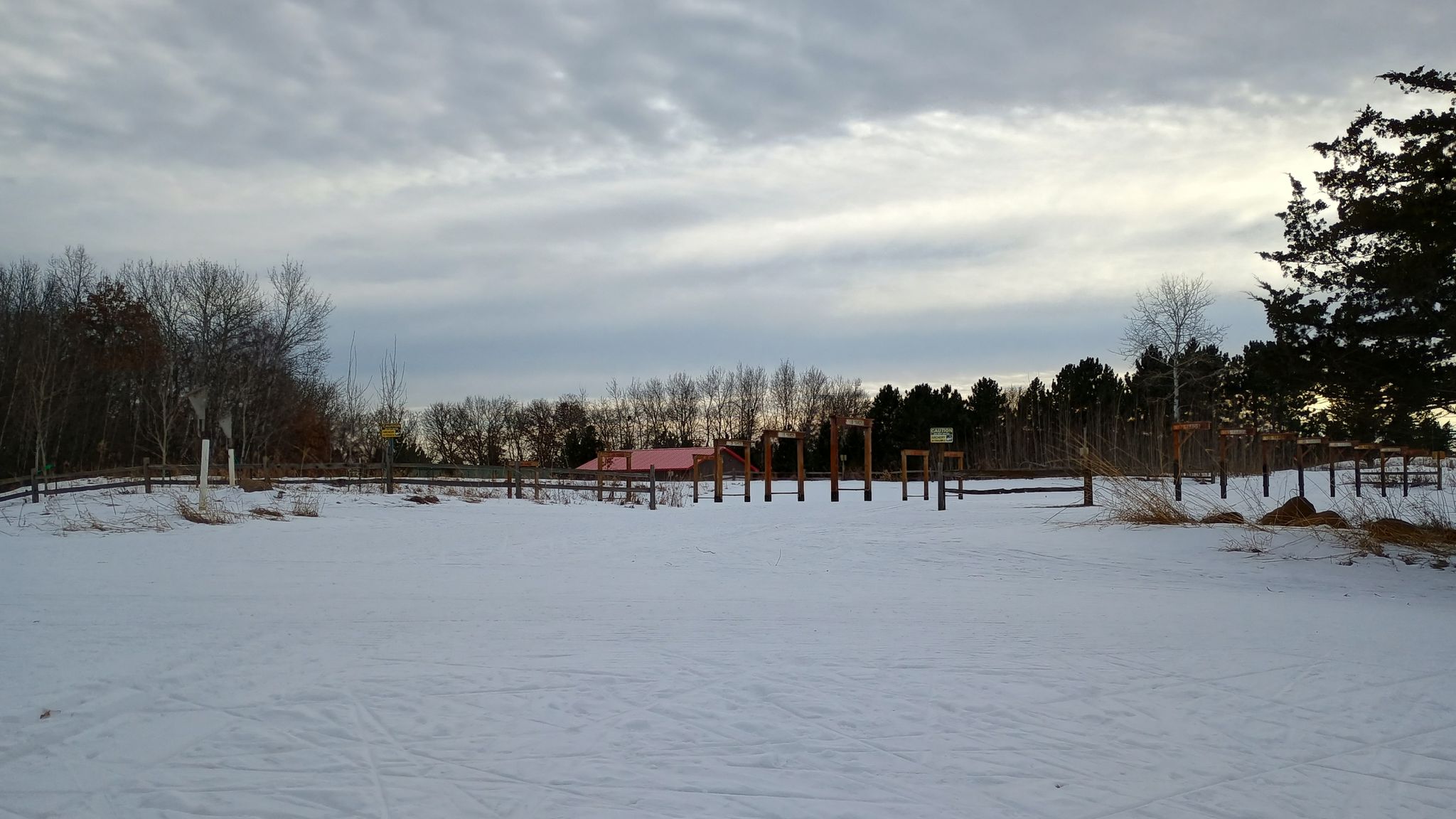 Snow-covered field with distant trees and a building under a cloudy winter sky. - Prairie, Poplar, and Wash Pond Flats Loop