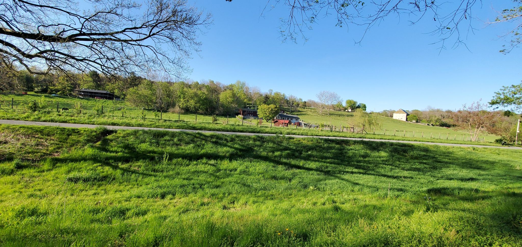 Expansive green field with distant trees and buildings under a bright sky. - Dam No. 4 – Horseshoe Bend campsite loop from Shepherdstown