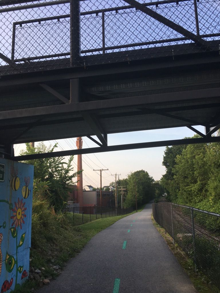 Paved path under a metal bridge, leading into a tree-lined area. - Ahern State Park Loop via WOW Trail