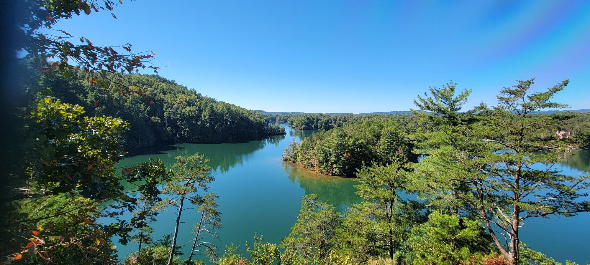 Panoramic view of a winding river through dense green forests under clear sky. - Raven Rock Trail