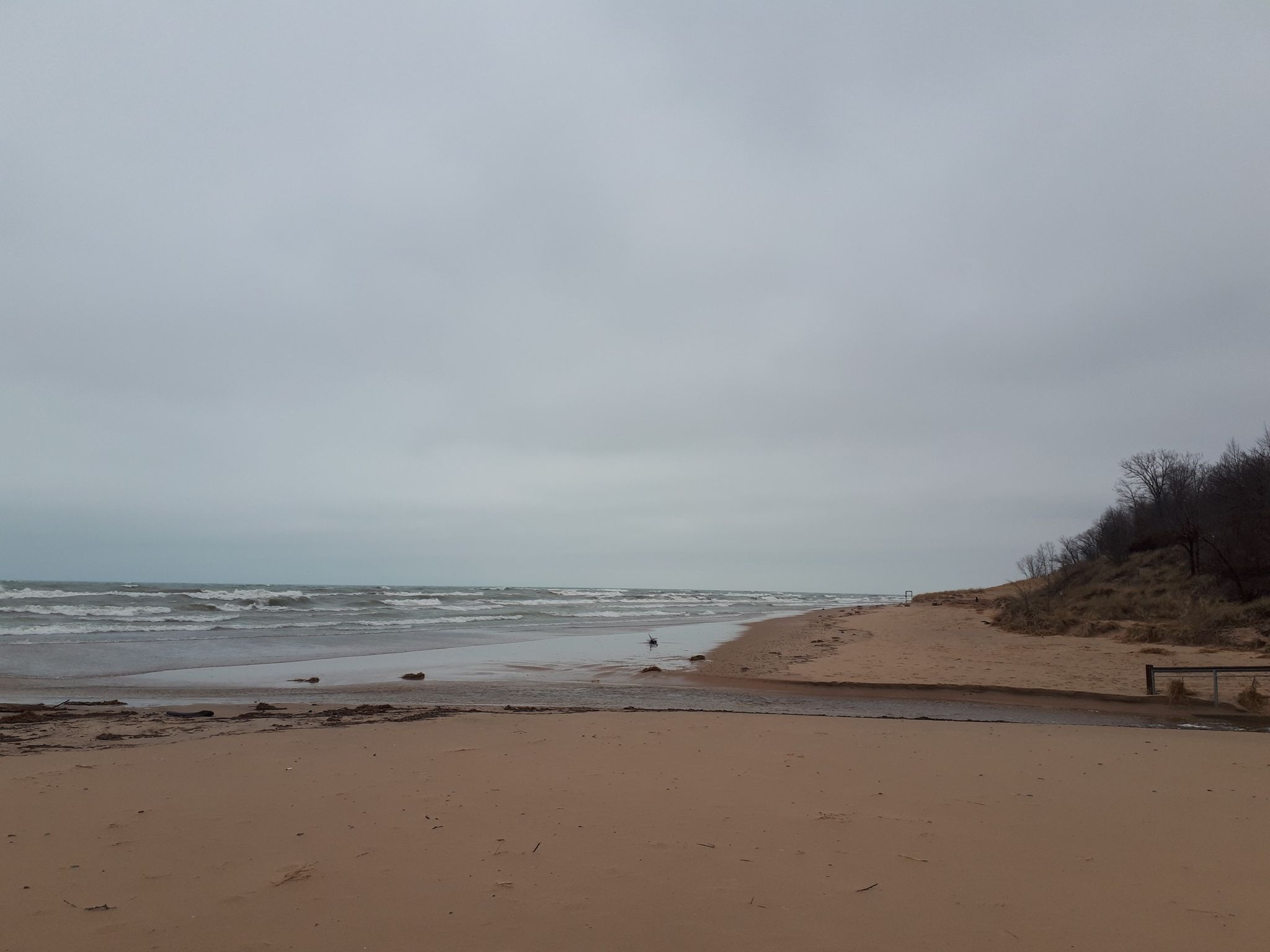 Wide sandy beach with choppy grey water and a dark dune under an overcast sky. - Picnic spot loop from Imagination Glen BMX