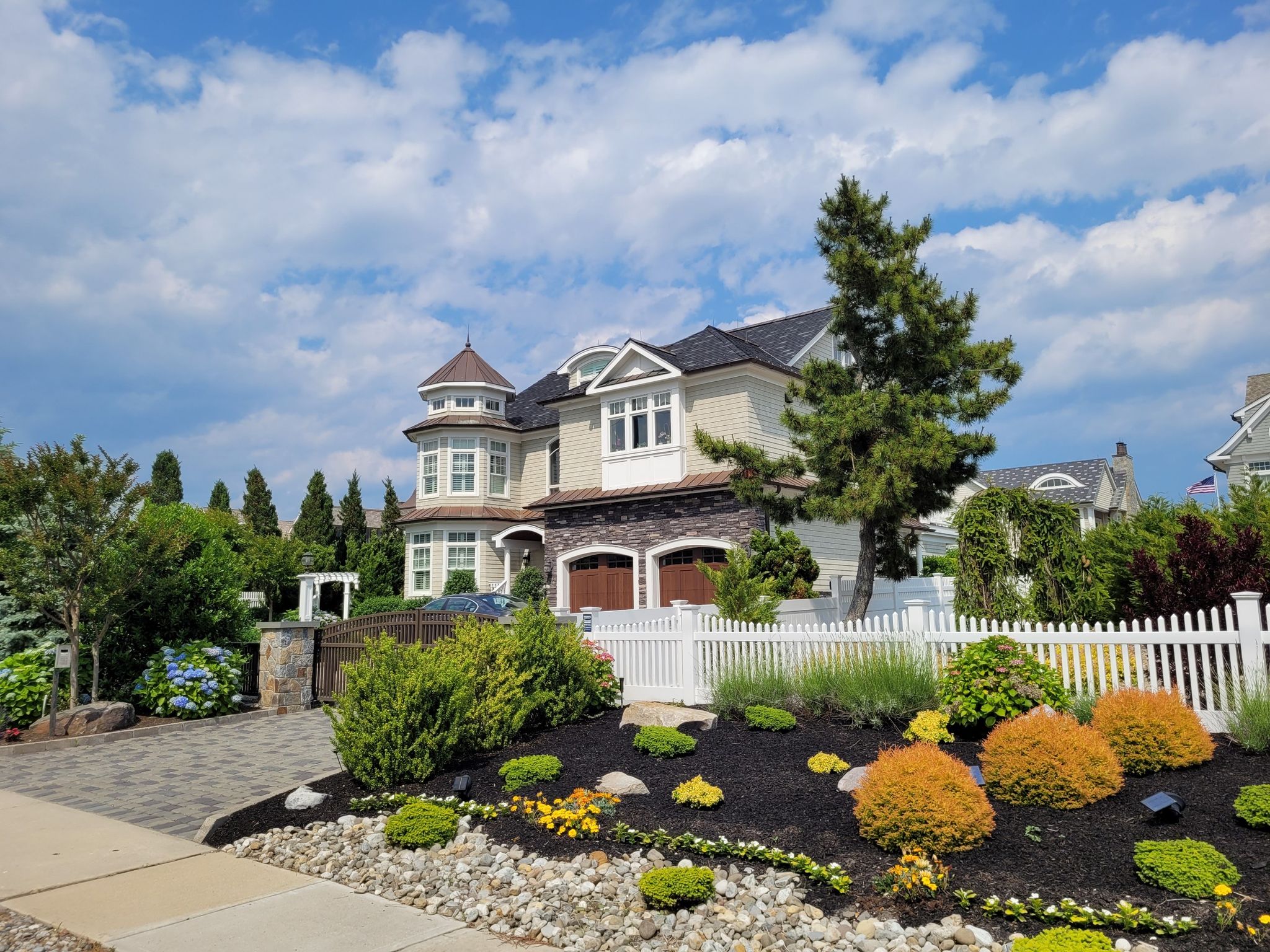 Large house with turret, landscaped yard, white fence under blue sky. - Island Beach State Park from Spring Lake via Point Pleasant Beach