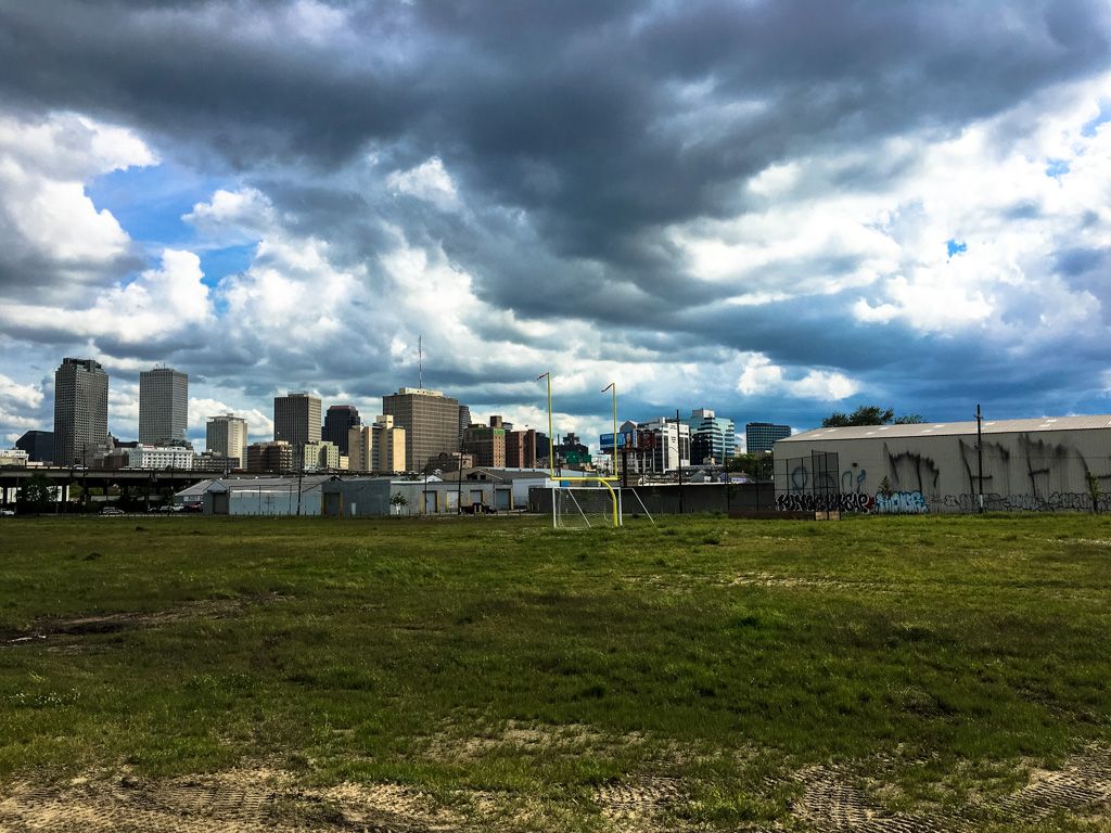Grassy field with a city skyline under dramatic, cloudy skies. - Port Pontchartrain Lighthouse