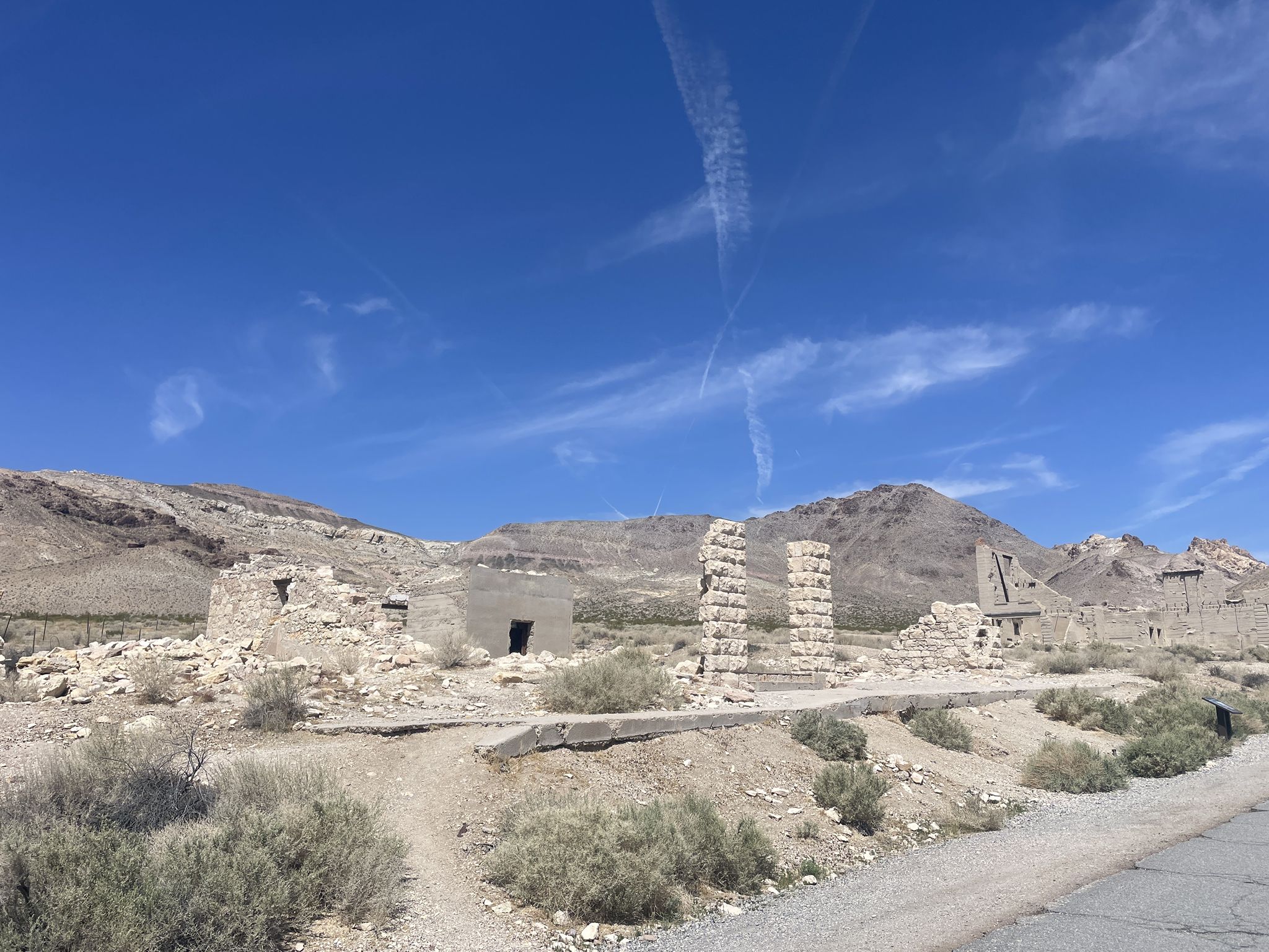 Scattered stone ruins and foundations in a vast, sunny desert landscape. - Rhyolite Ghost Town & Goldwell Open Air Museum Loop