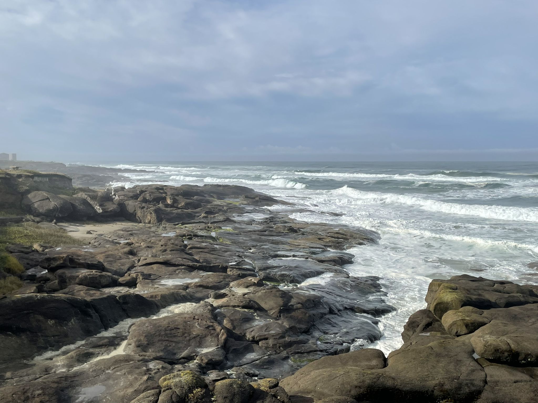 Wide view of a rocky shoreline with powerful ocean waves under a cloudy sky. - Oregon Coast Trail 804 loop from Yachats Ocean Road State Natural Site