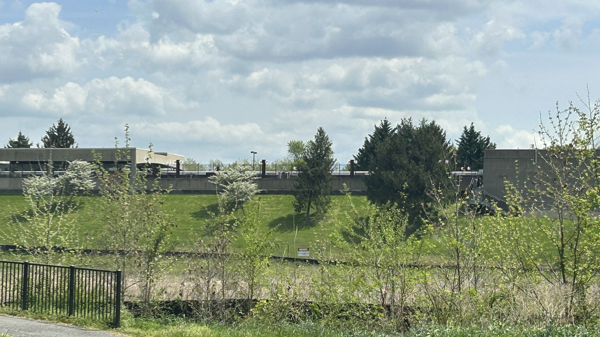 Grassy hill with buildings and trees under a cloudy sky. - Sligo Creek Trail – Carroll Avenue Bridge loop from Riverdale
