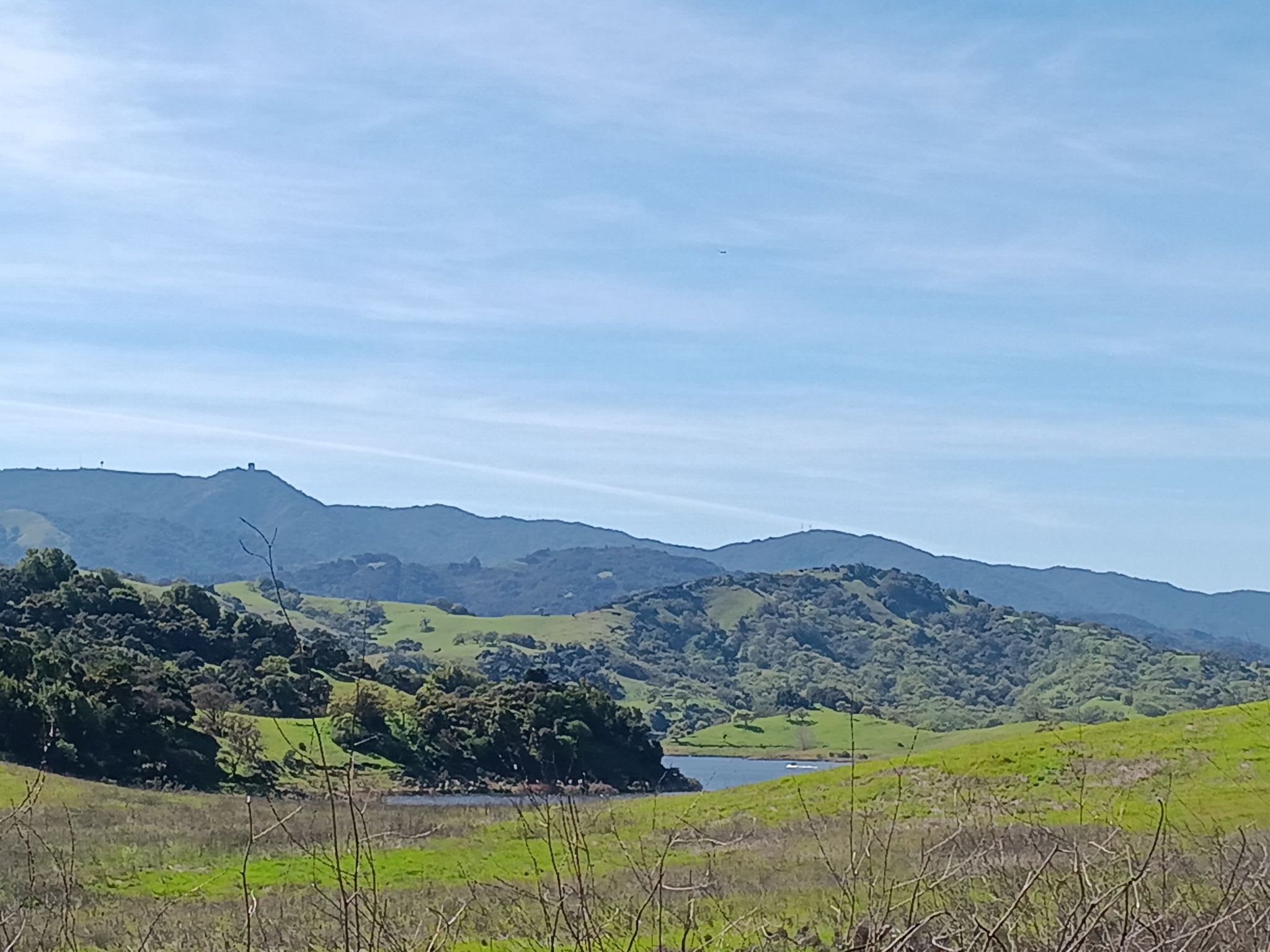 Green rolling hills and a lake under a bright blue sky. - Coyote Creek and Los Alamitos Creek Trail Loop