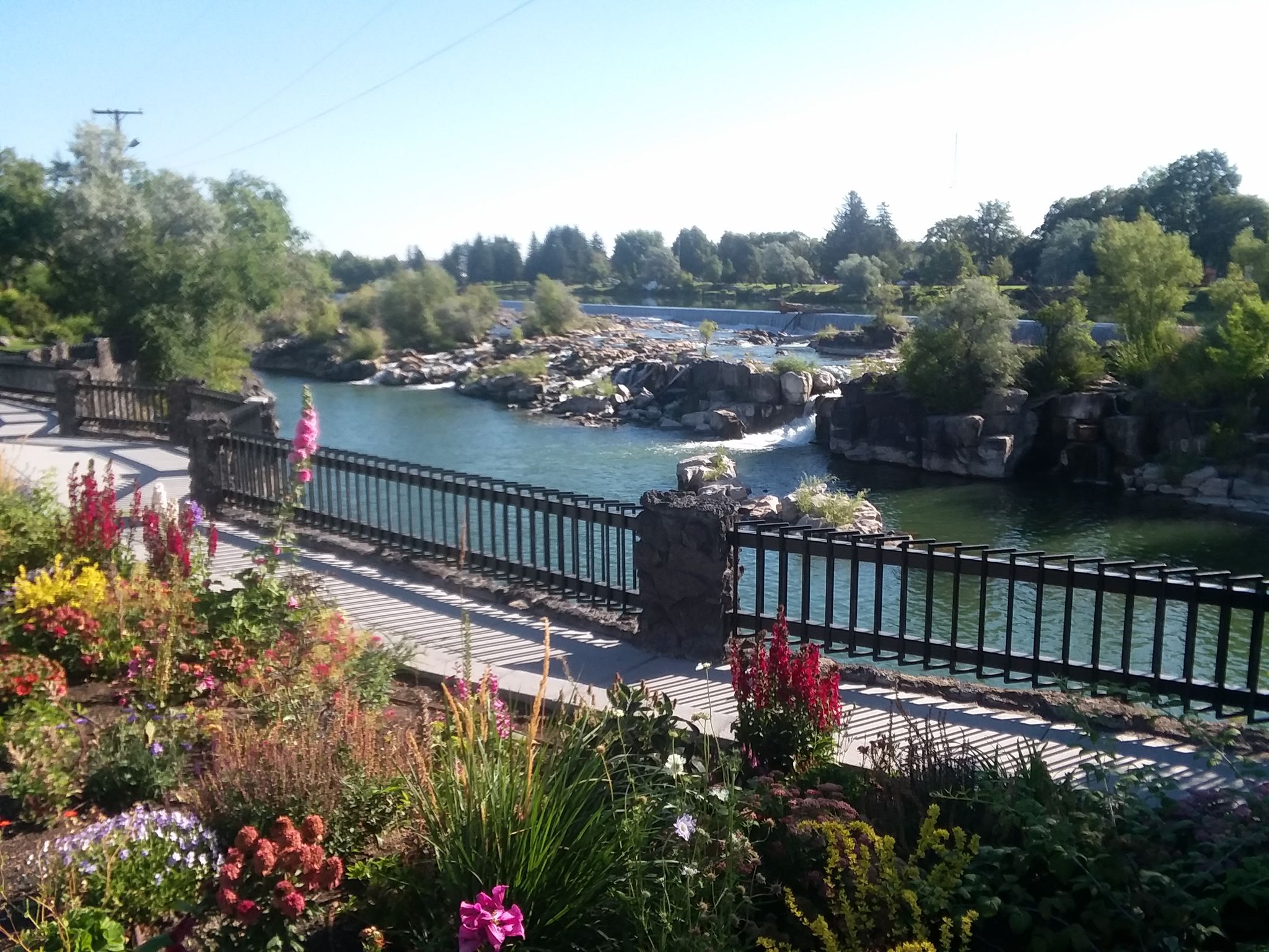 Colorful flower garden next to a fenced walkway overlooking river rapids. - Friendship Garden – Idaho Falls loop from Idaho Falls