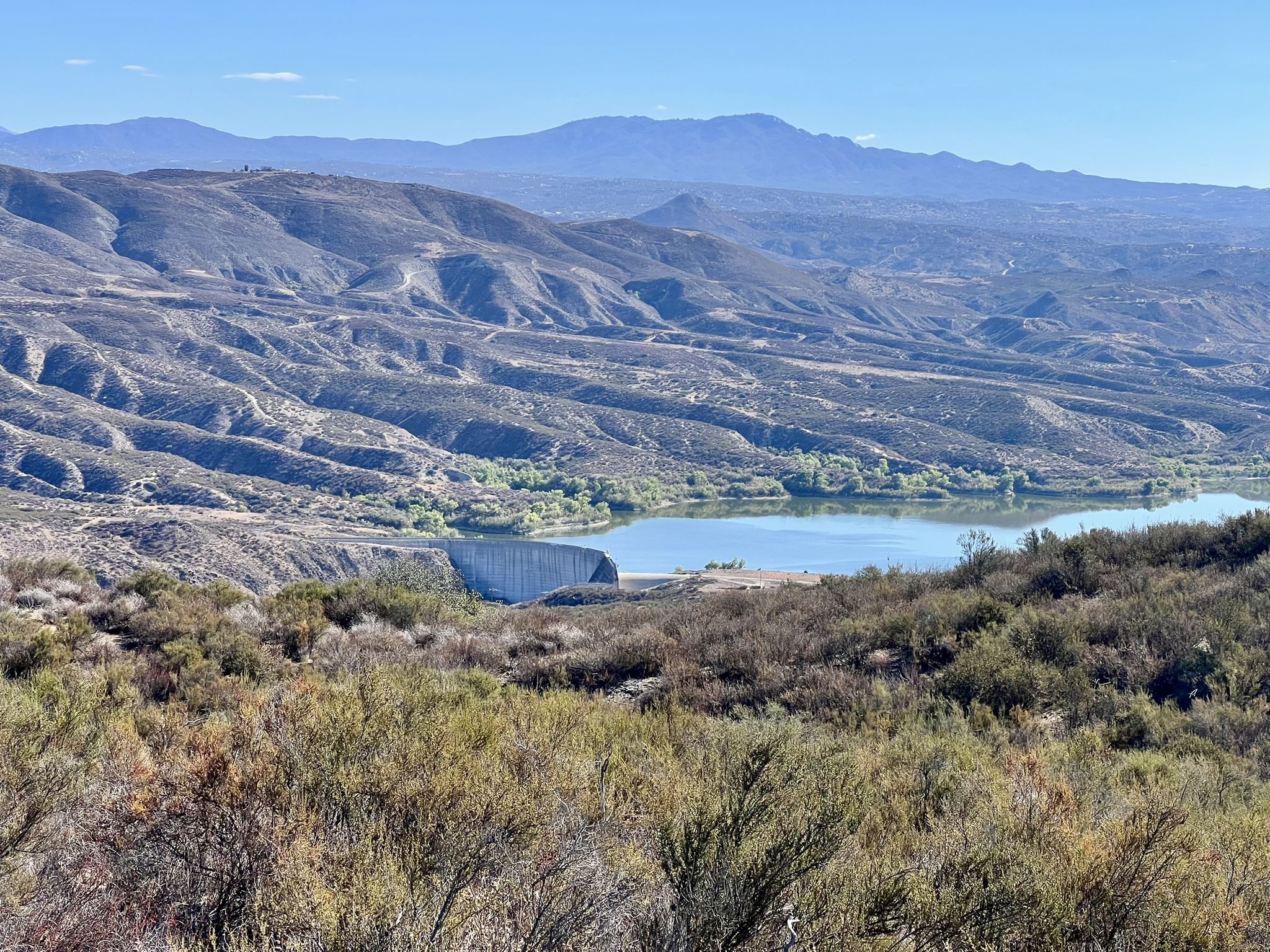 Lake with a dam structure, surrounded by arid hills and distant mountains. - Oak Mountain – Gravel Road loop from Dripping Springs