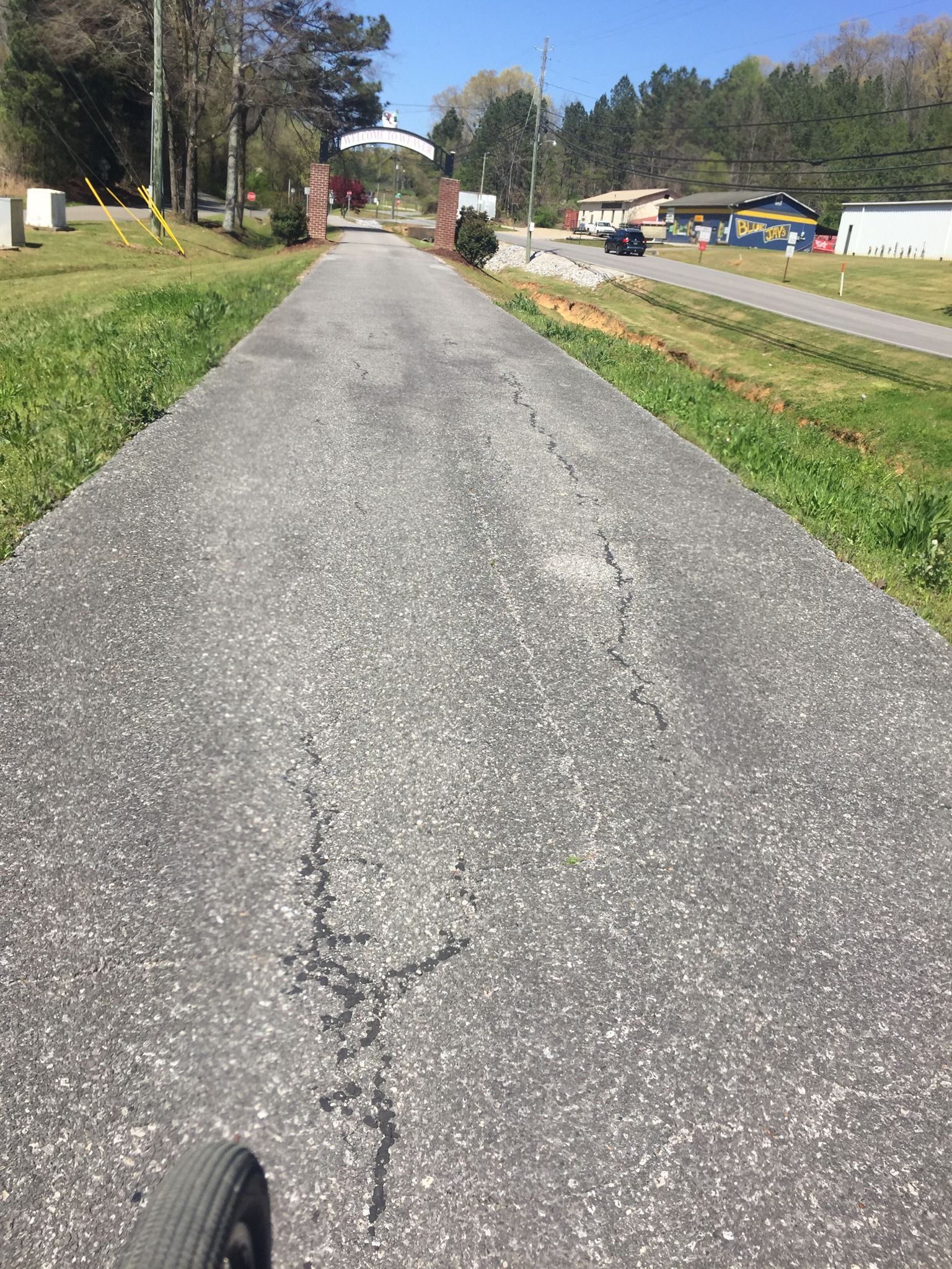 Cracked paved path leading to a distant archway on a sunny day. - Wygant Hill – Jacksonville Train Depot loop from Anniston