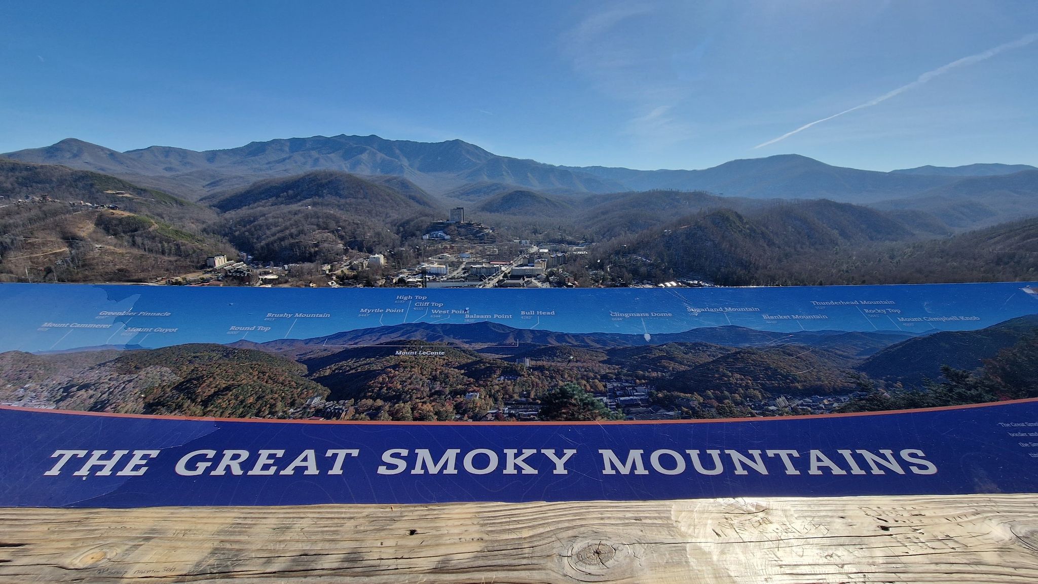 A wide mountain range vista under a clear blue sky, with an informational sign. - Gatlinburg SkyTrail
