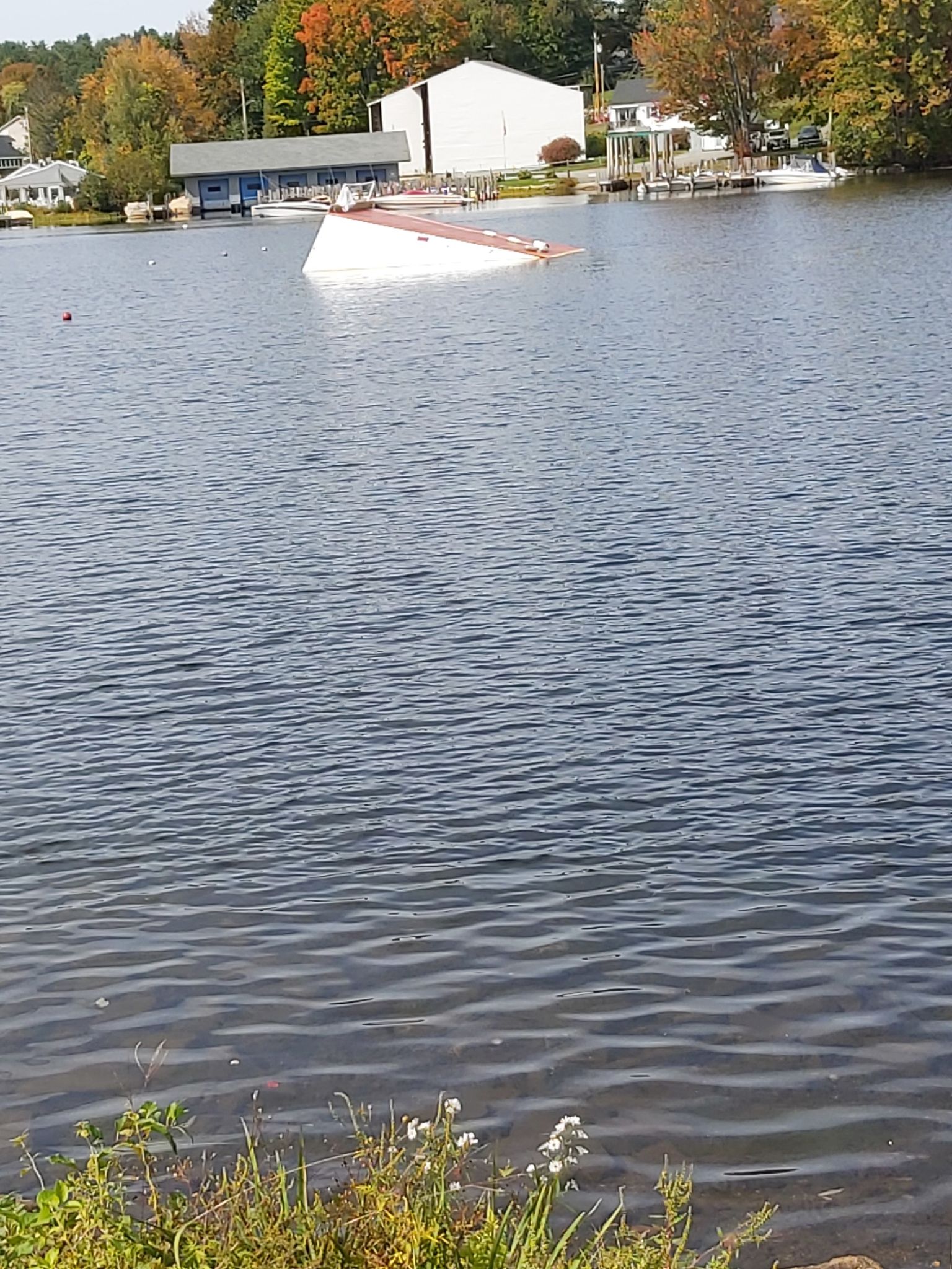 A partially submerged boat in a lake with houses on the far shore. - Lake Wentworth – Back Bay loop from Wolfeboro