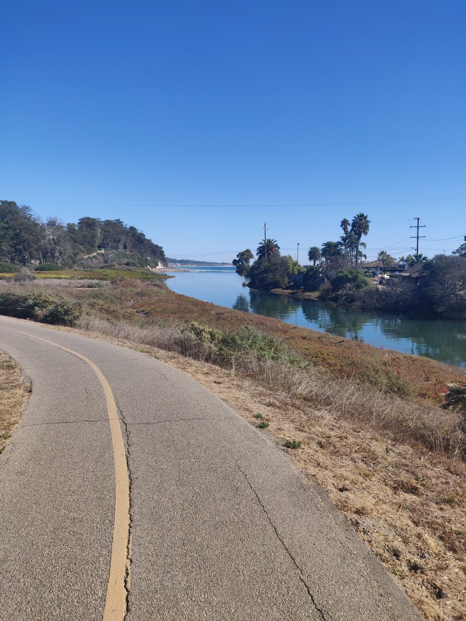 Paved path next to a calm river with lush and dry vegetation under clear sky. - Modoc Road Multi-use Bike Path – Obern Trail loop from Hillside House