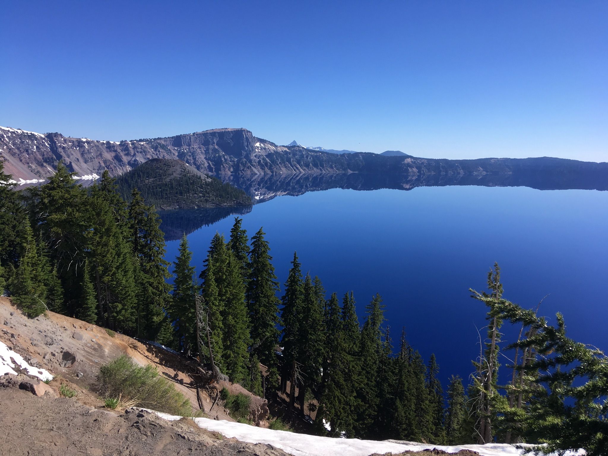 Deep blue lake reflecting the sky, surrounded by pine trees and snowy slopes. - Rim Village to Vidae Falls