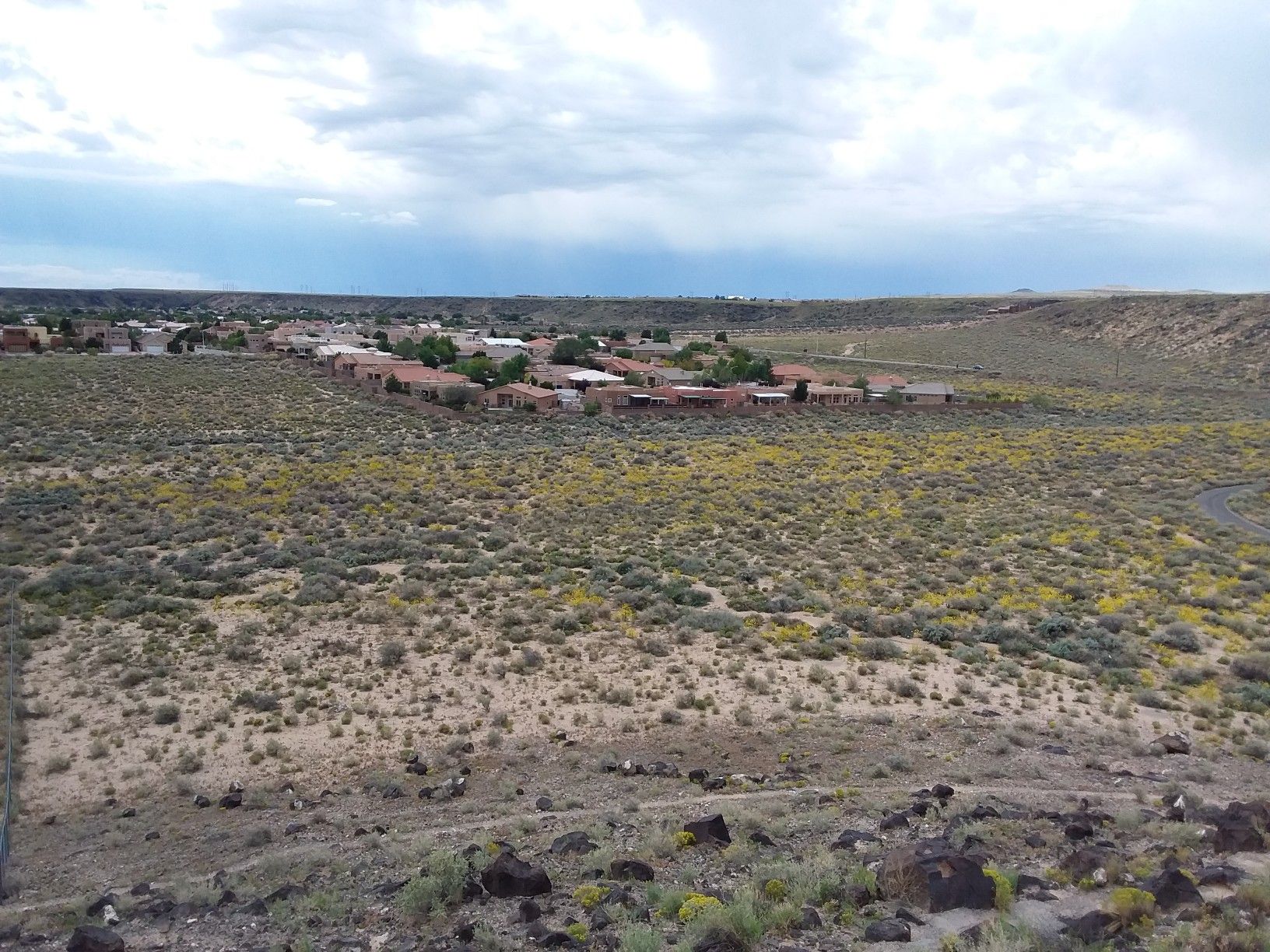 Overcast sky above a distant town in a vast, arid landscape. - Mesa Point Trail