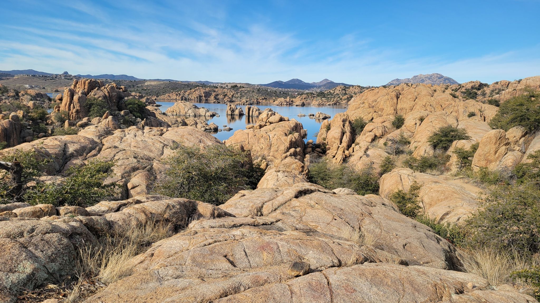 Rocky landscape with a lake and distant hills under a partly cloudy sky. - Peavine Trail and Watson Lake Loop