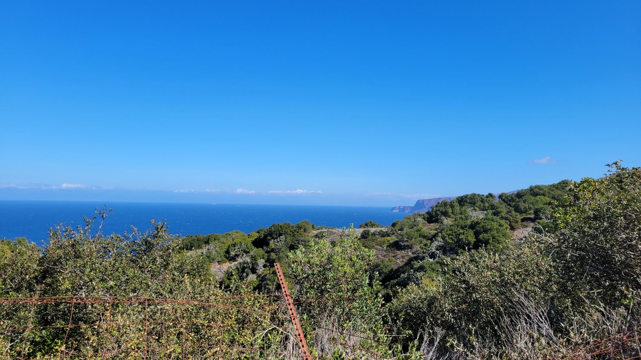 Vast blue ocean and sky over green coastal hills on a clear day. - Del Norte Trail