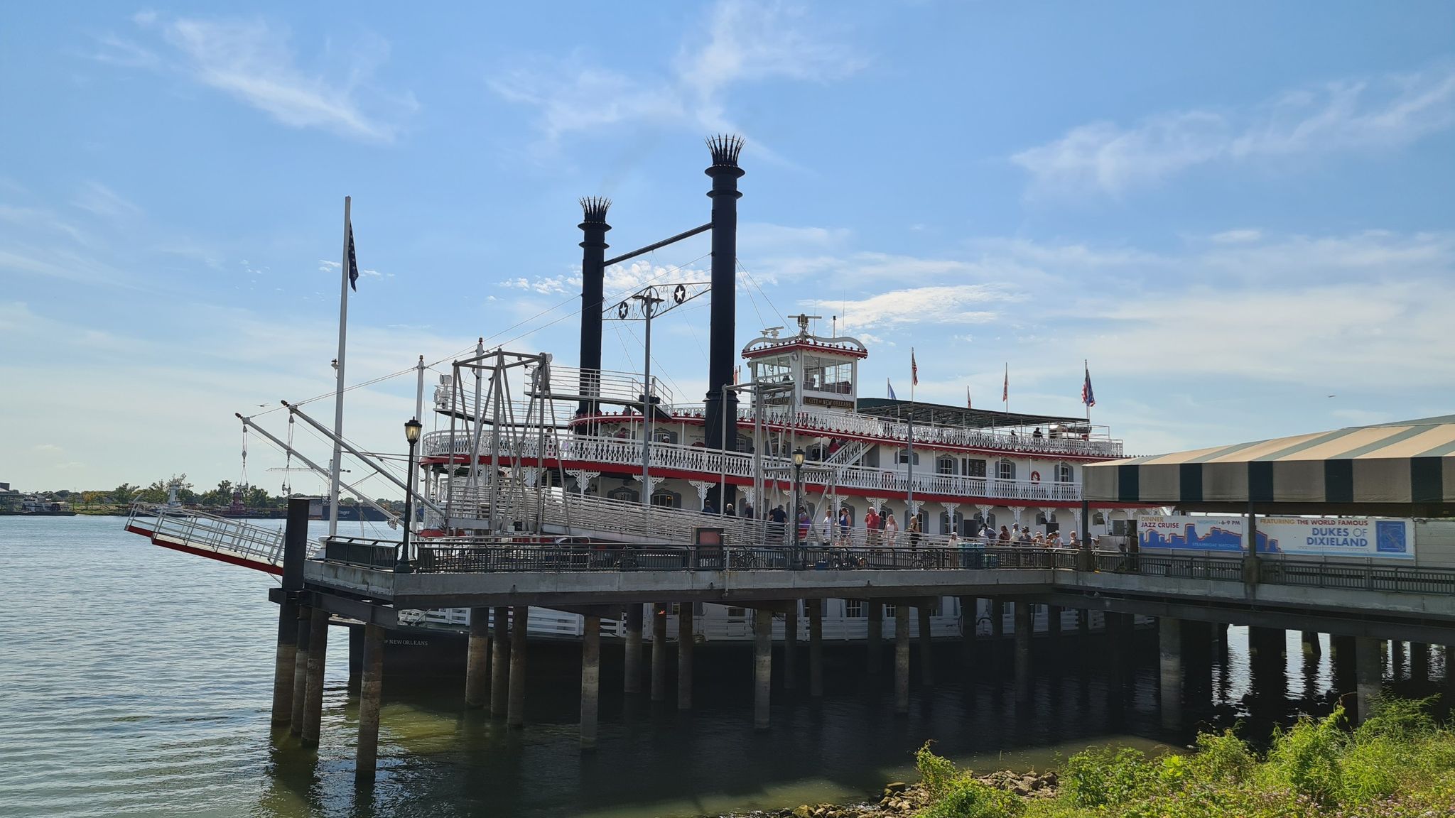 A large paddlewheel boat docked at a pier on a bright, sunny day. - Steamboat Natchez – Royal Street, New Orleans loop from New Orleans