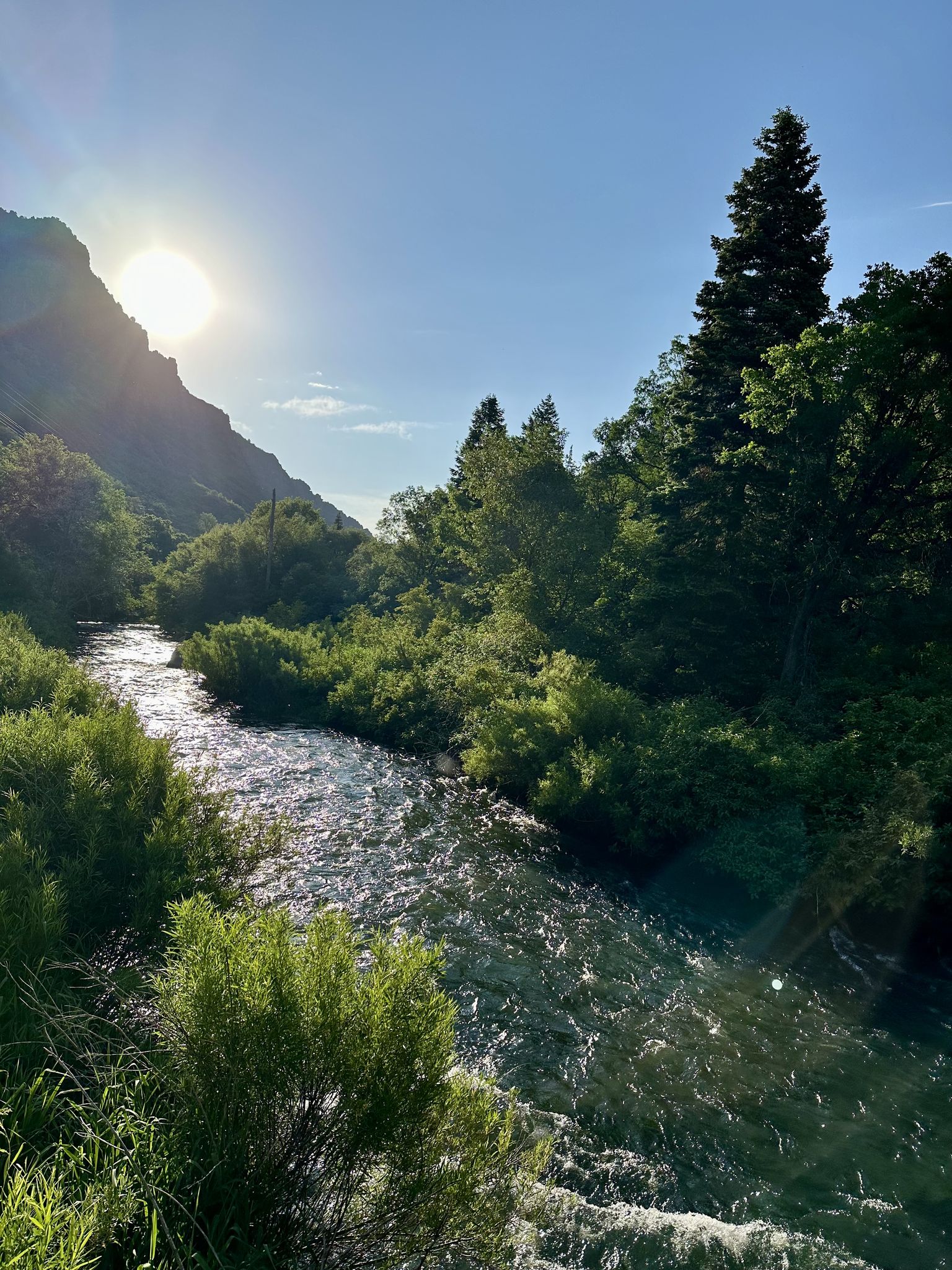 Sun shines over a winding river flowing through a green mountain valley. - Denver and Rio Grande Western Rail Trail