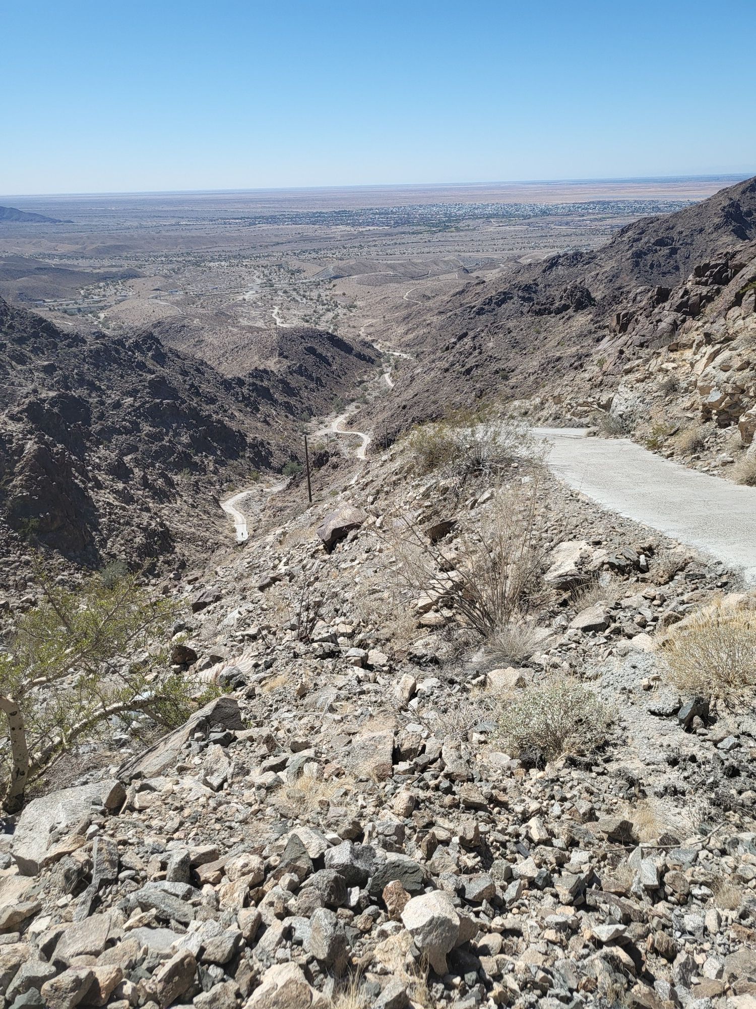 Winding road descends through a rocky, arid canyon under a clear sky. - Telegraph Pass Trail