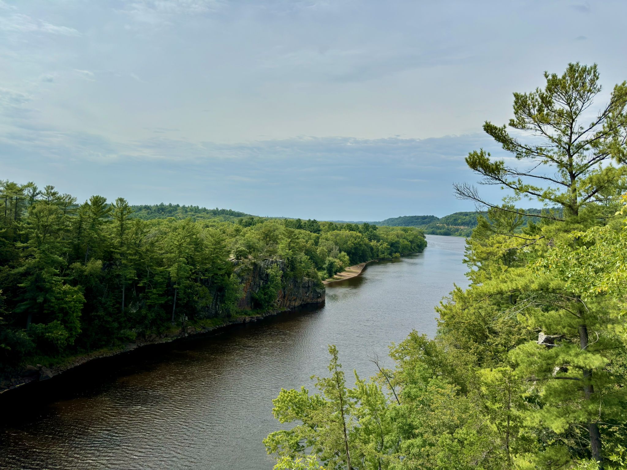Wide river winding through dense green forest under a cloudy sky. - Railroad and Walter F. Mondale River Trail Loop