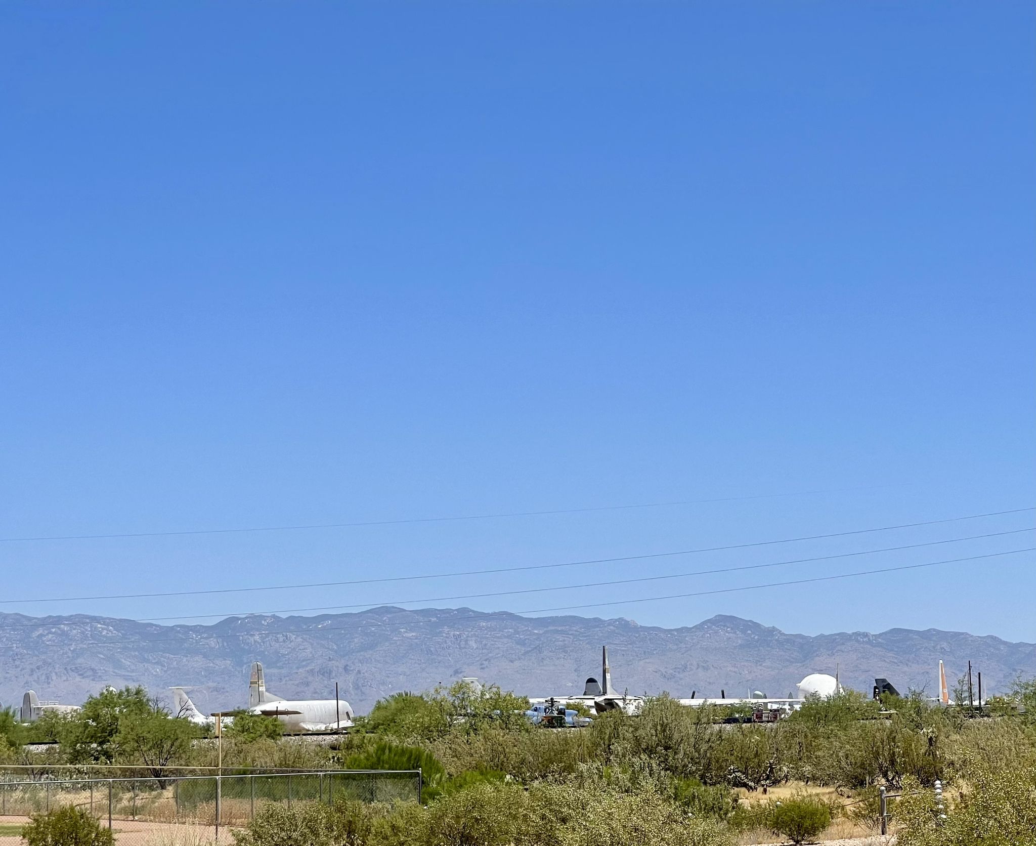 Distant airplanes and desert shrubs with mountains under a clear sky. - Julian Wash Greenway loop from Tucson International Airport