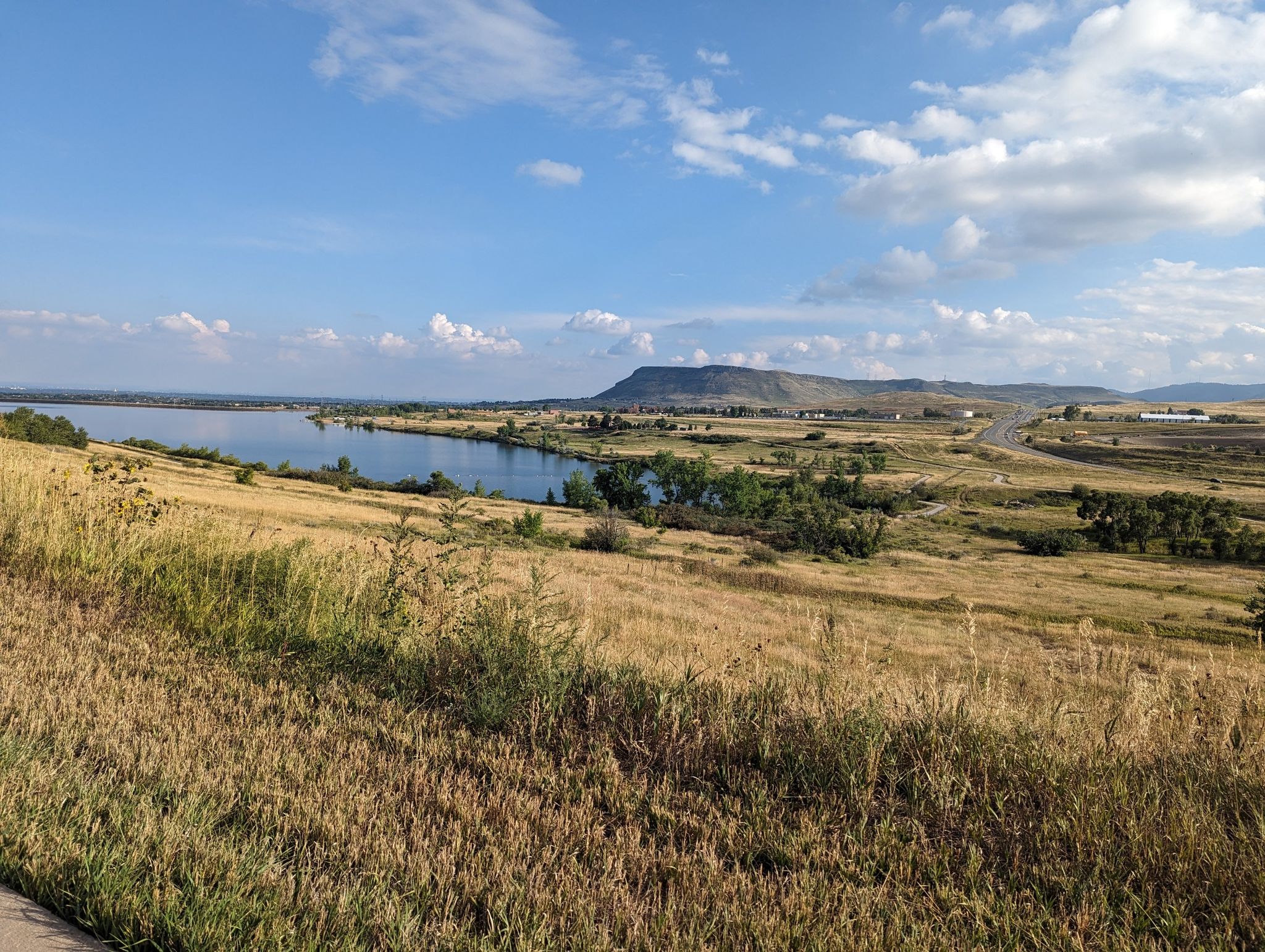 Sunny landscape with a large lake, golden hills, and distant mountains under blue sky. - Bridge into Golden – Clear Creek Trail loop from 60th & Sheridan - Arvada Gold Strike