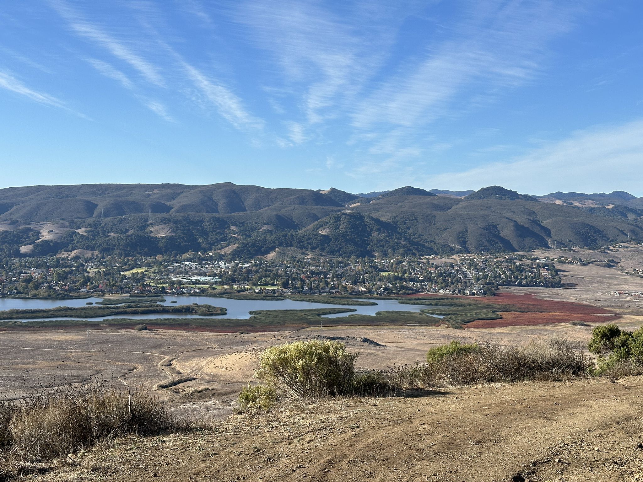 Panoramic view of a valley with a winding lake, distant mountains, and clear sky. - Laguna Lake and Cerro San Luis Loop Trail