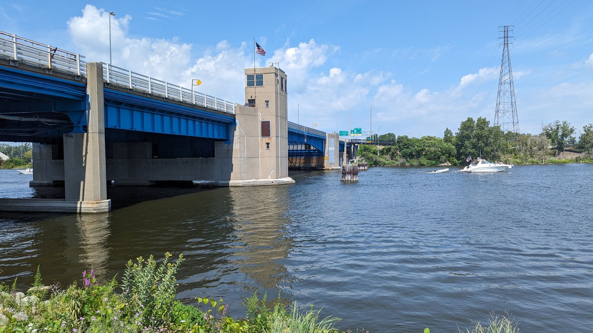 Blue bridge over water with boats, under a bright sky. - Fishing Dock at Pomona Park – Petty's Bayou Bridge loop from Grand Haven