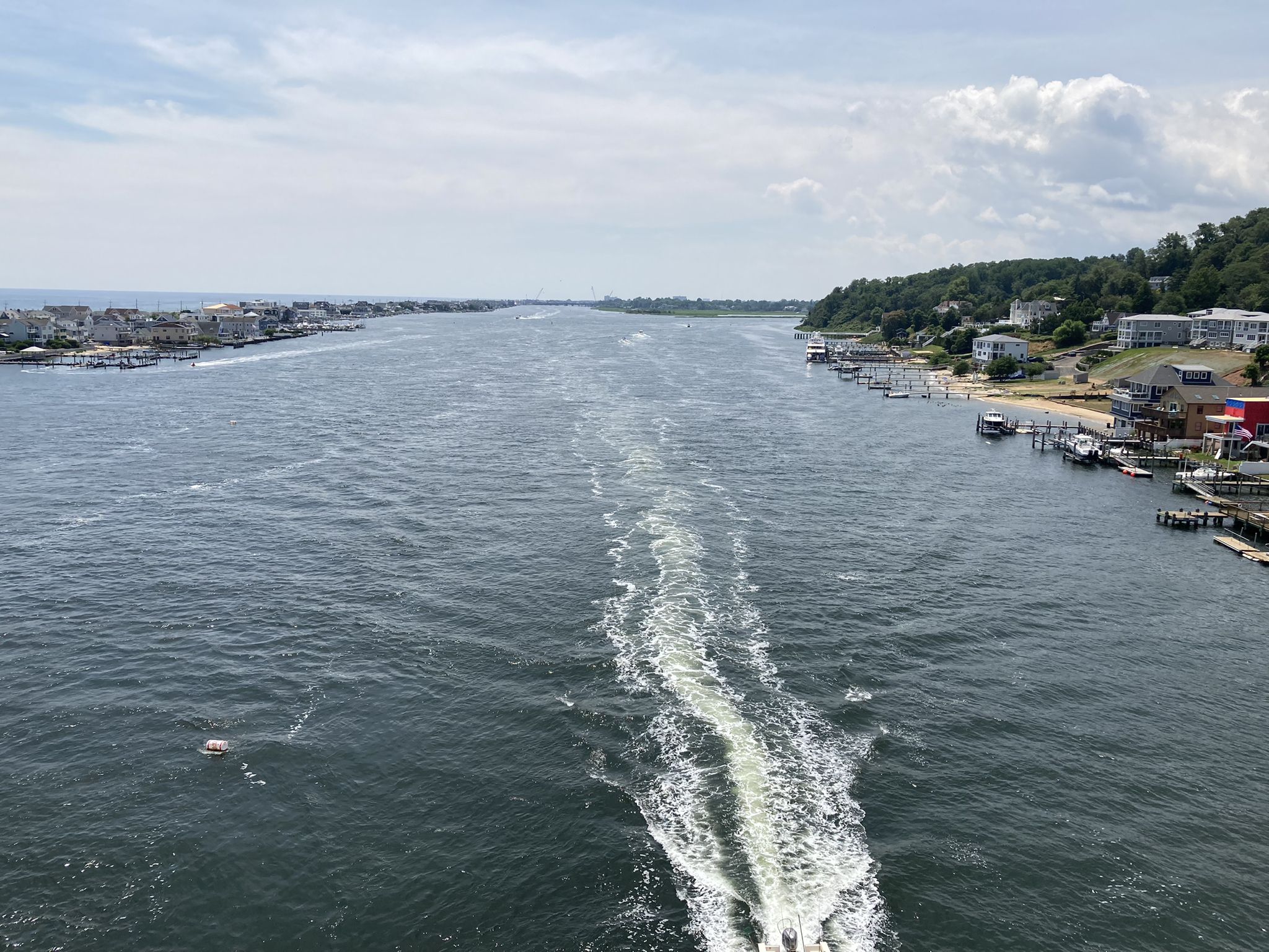 Wide river with a boat's white wake, houses on distant shores. - Shrewsbury River Bridge – Highlands Beach loop from Highlands