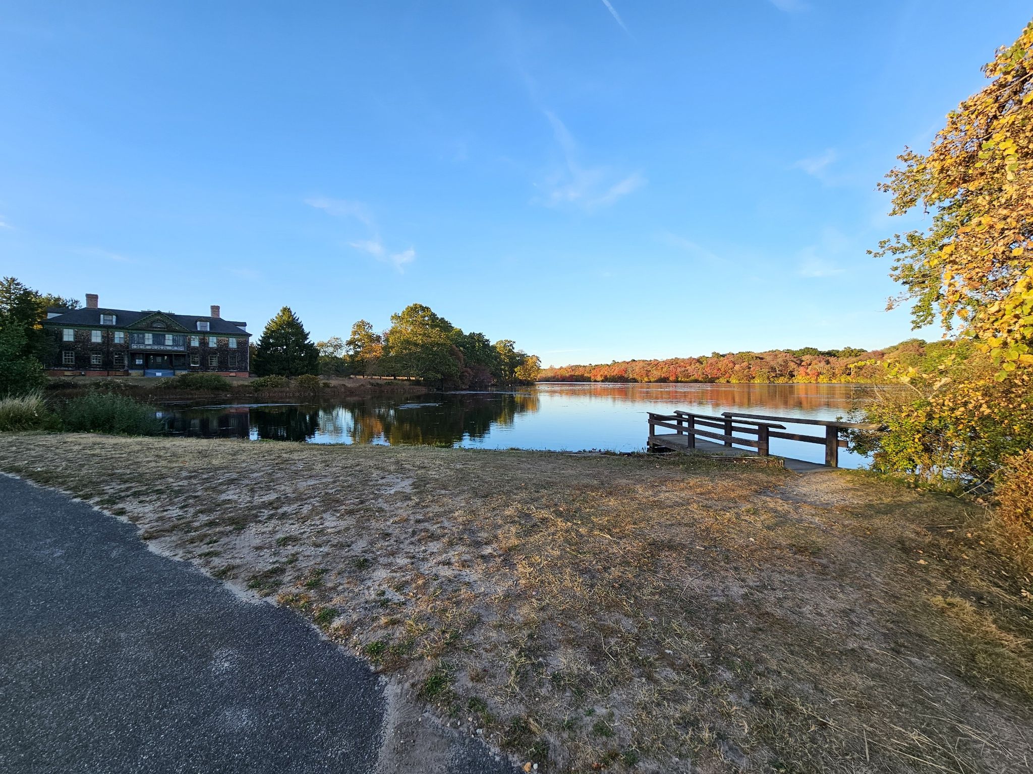 Sunny autumn day with a large house overlooking a calm lake and dock. - Bunce's Bridge – Nicoll Grist Mill loop from Village of Islandia