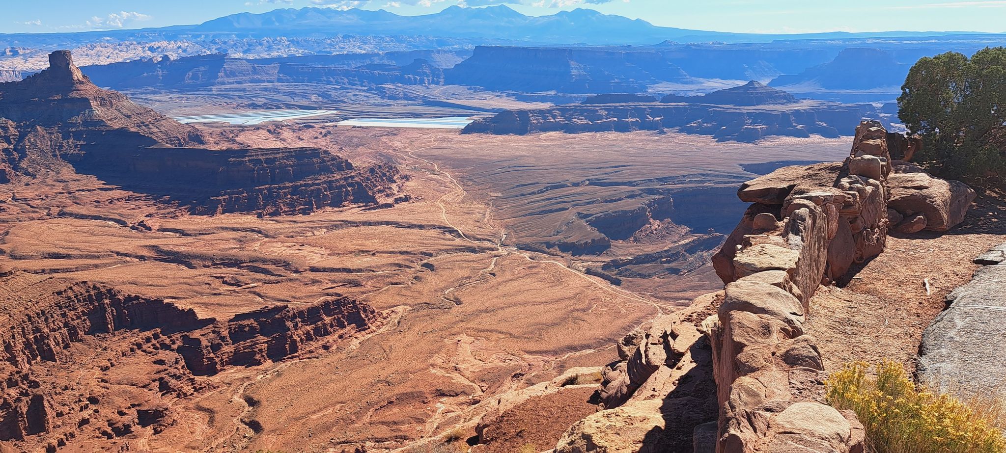 Panoramic desert canyon with distant mountains and blue lakes under a clear sky. - Meander Overlook loop from Dead Horse Point State Park