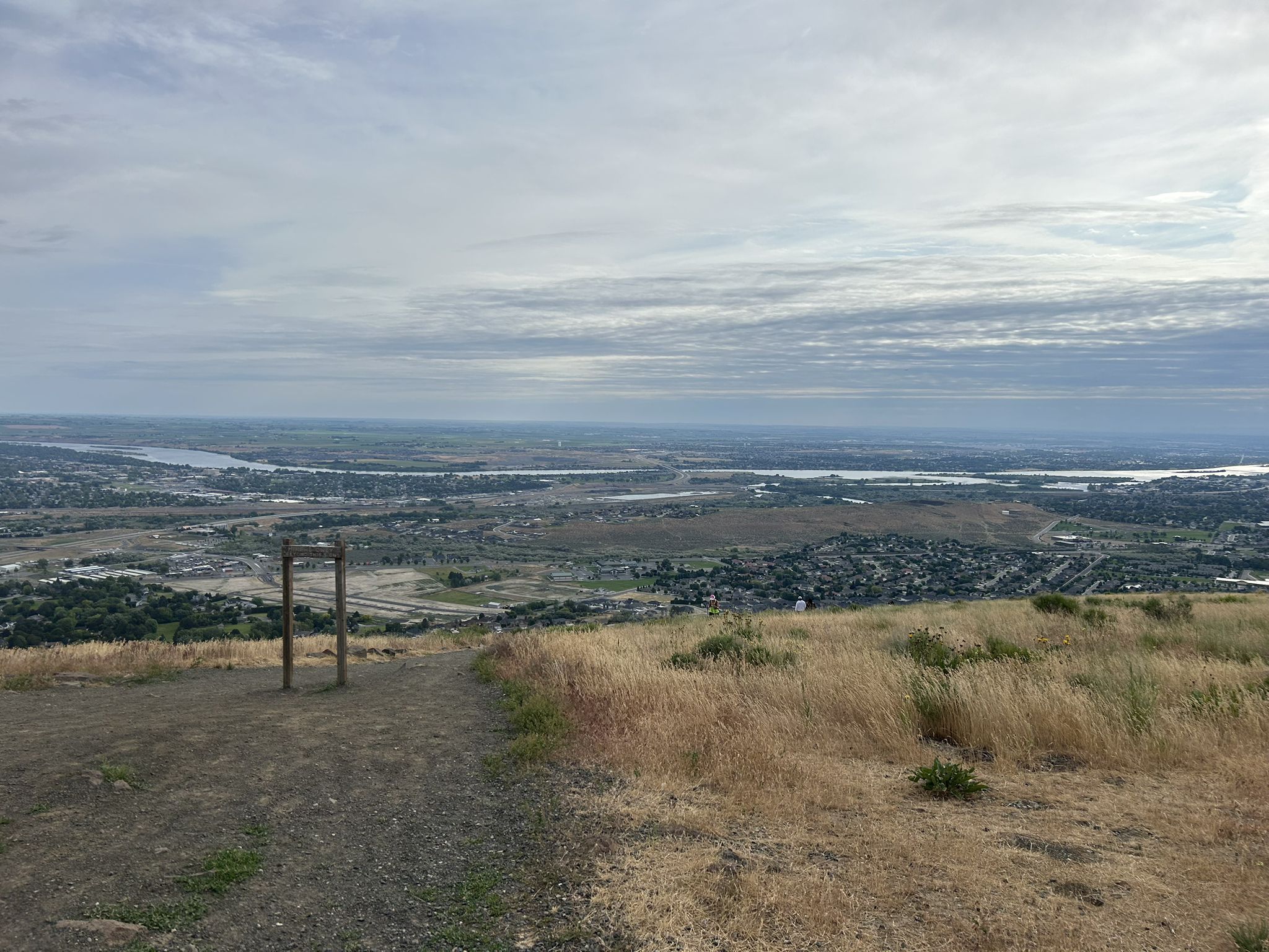 Overcast sky above a vast valley with a river and distant town. - Badger Skyline Trail