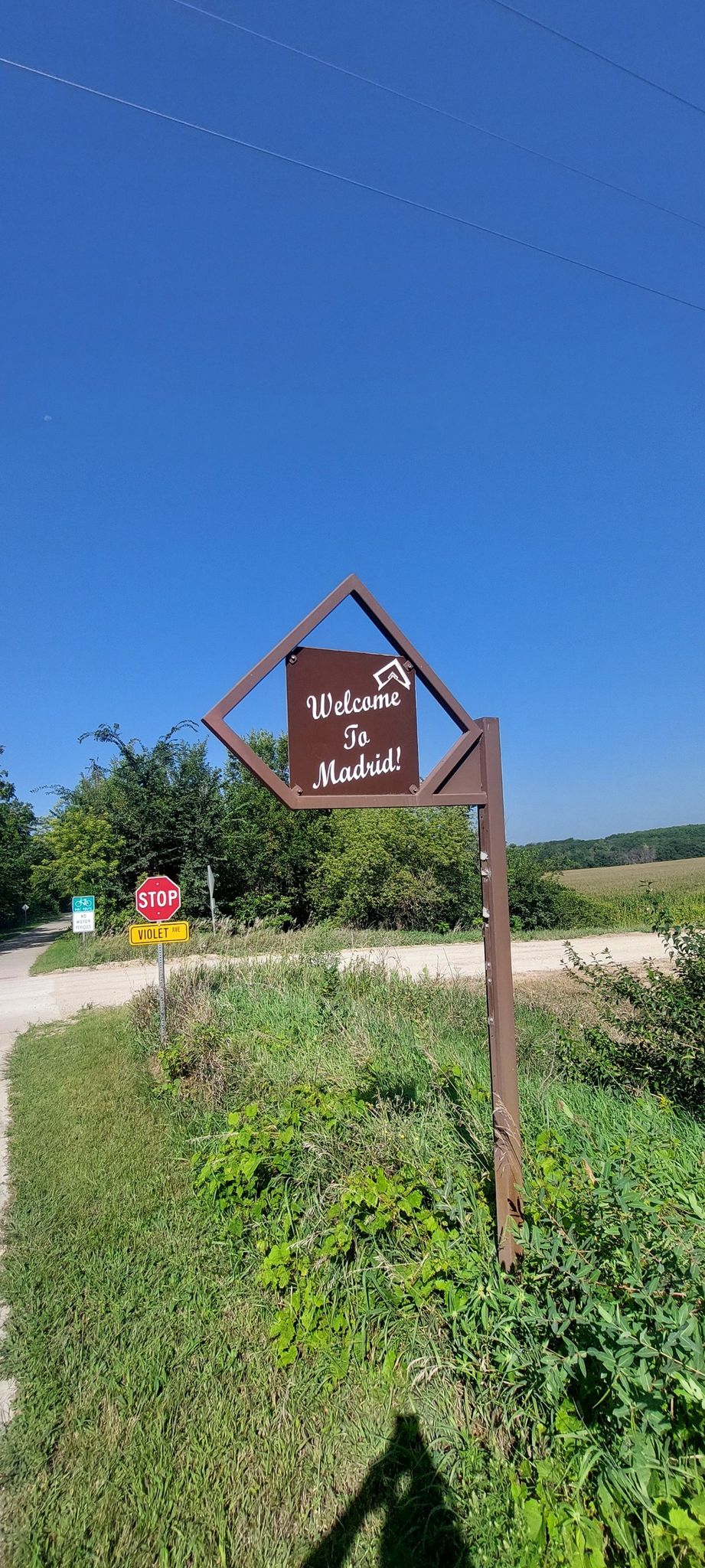 Welcome sign on a post in a grassy area under a bright blue sky. - Ankeny Welcome Sign – High Trestle Trail loop from Ankeny