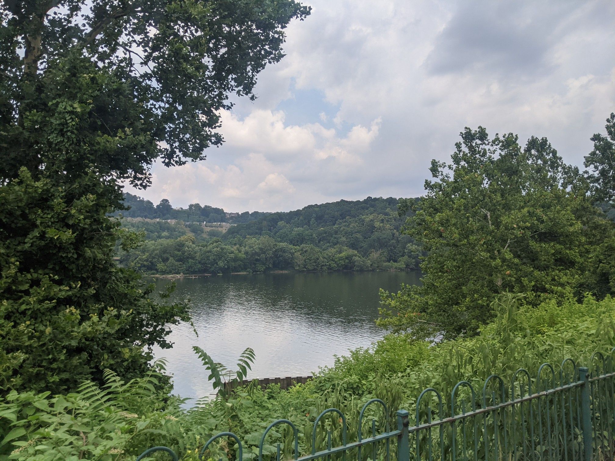 A serene lake surrounded by lush green trees under a cloudy sky. - Three Rivers Heritage Trail – Three Rivers Heritage Trail loop from Homestead