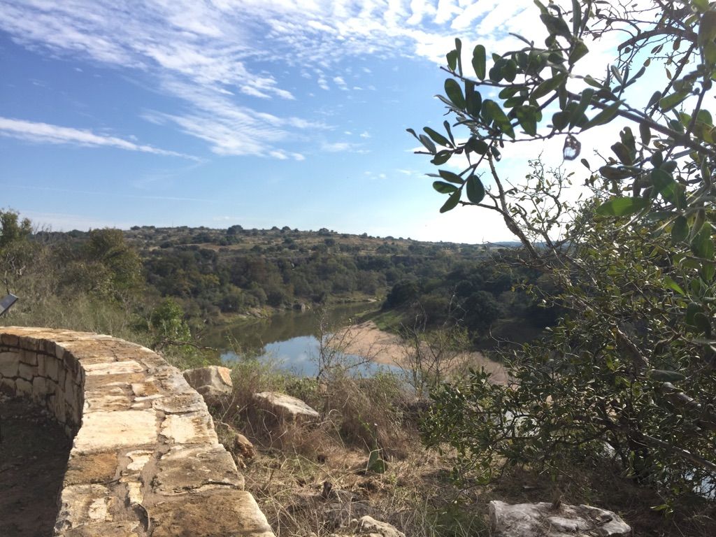 Sunny view of a river winding through a green valley with a stone wall. - Reimers Ranch Granite Trail, Climbers Canyon, and Upper River Trail