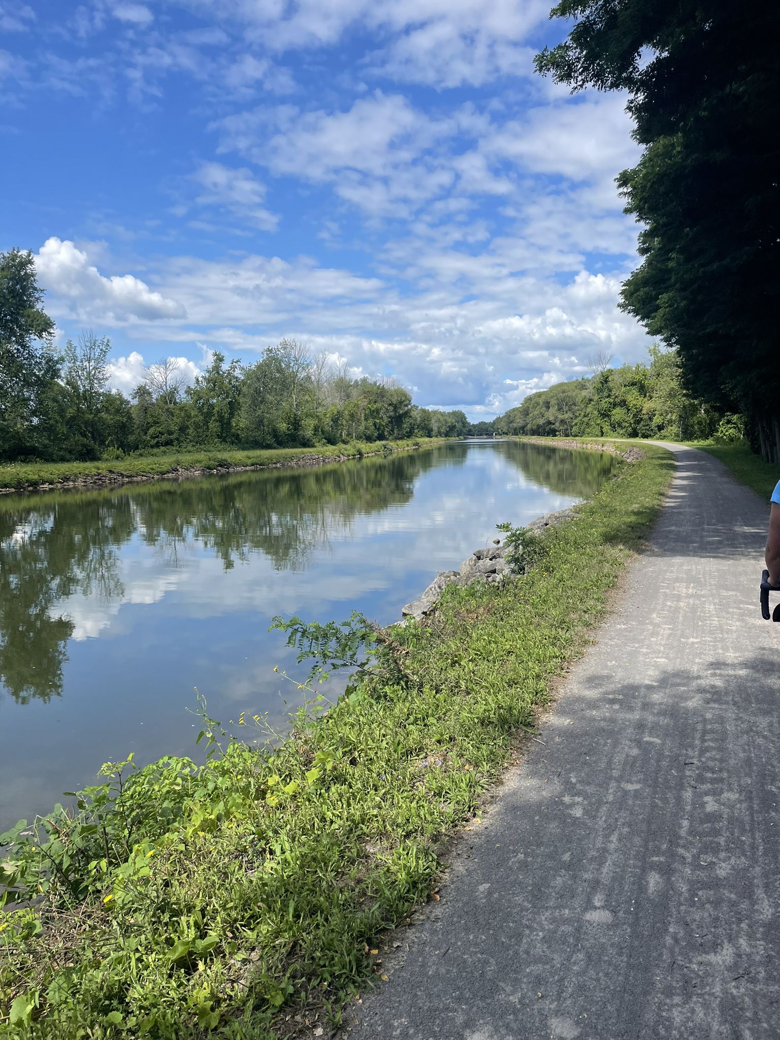 A canal alongside a paved path, with trees under a cloudy sky. - Holley Lift Bridge loop from Village of Brockport