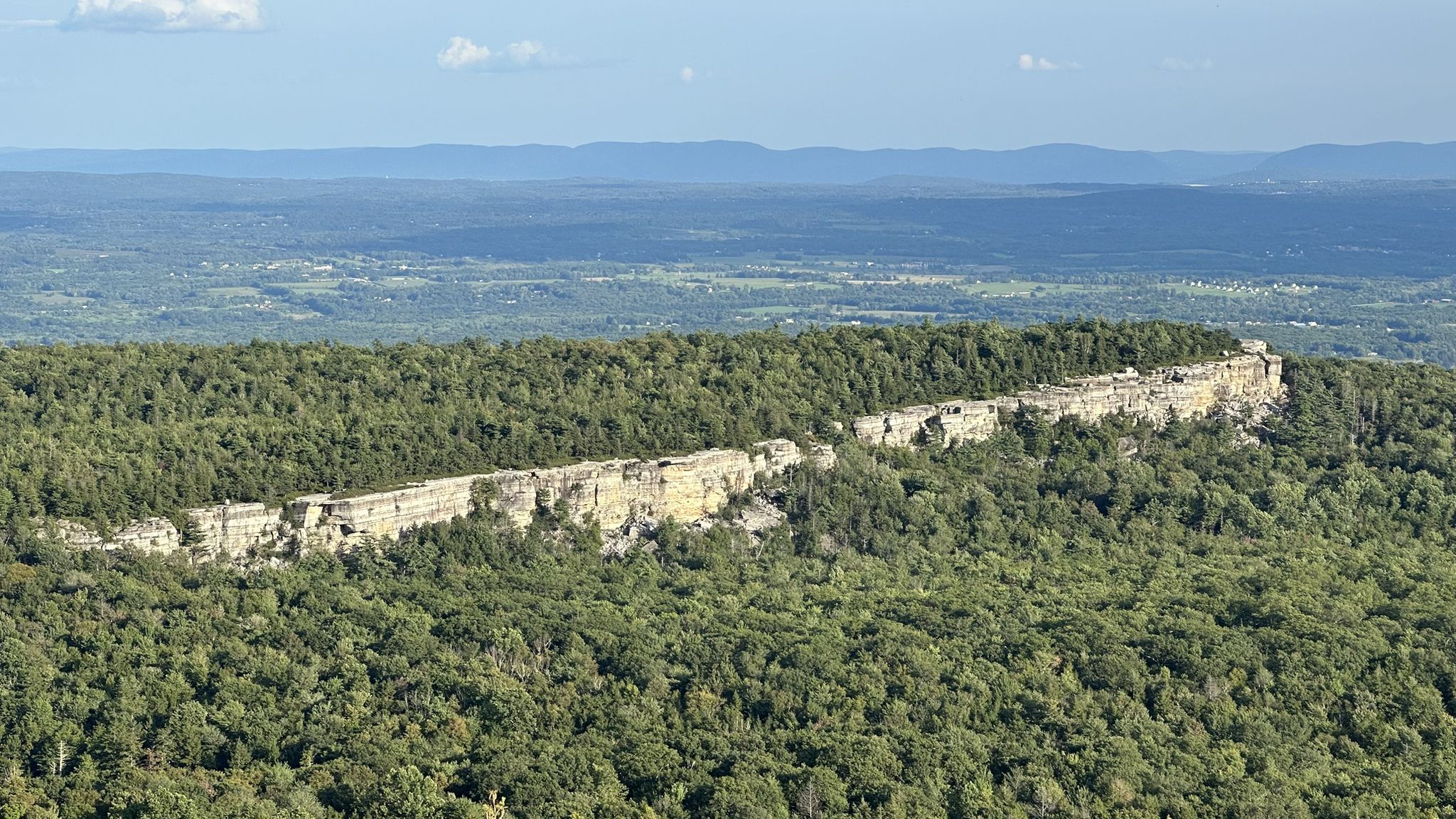 Elevated view of a long rocky ridge covered in dense green forest. - Castle Point – Lake Minnewaska loop from Horse Trailer Lot/Awosting Parking Overflow