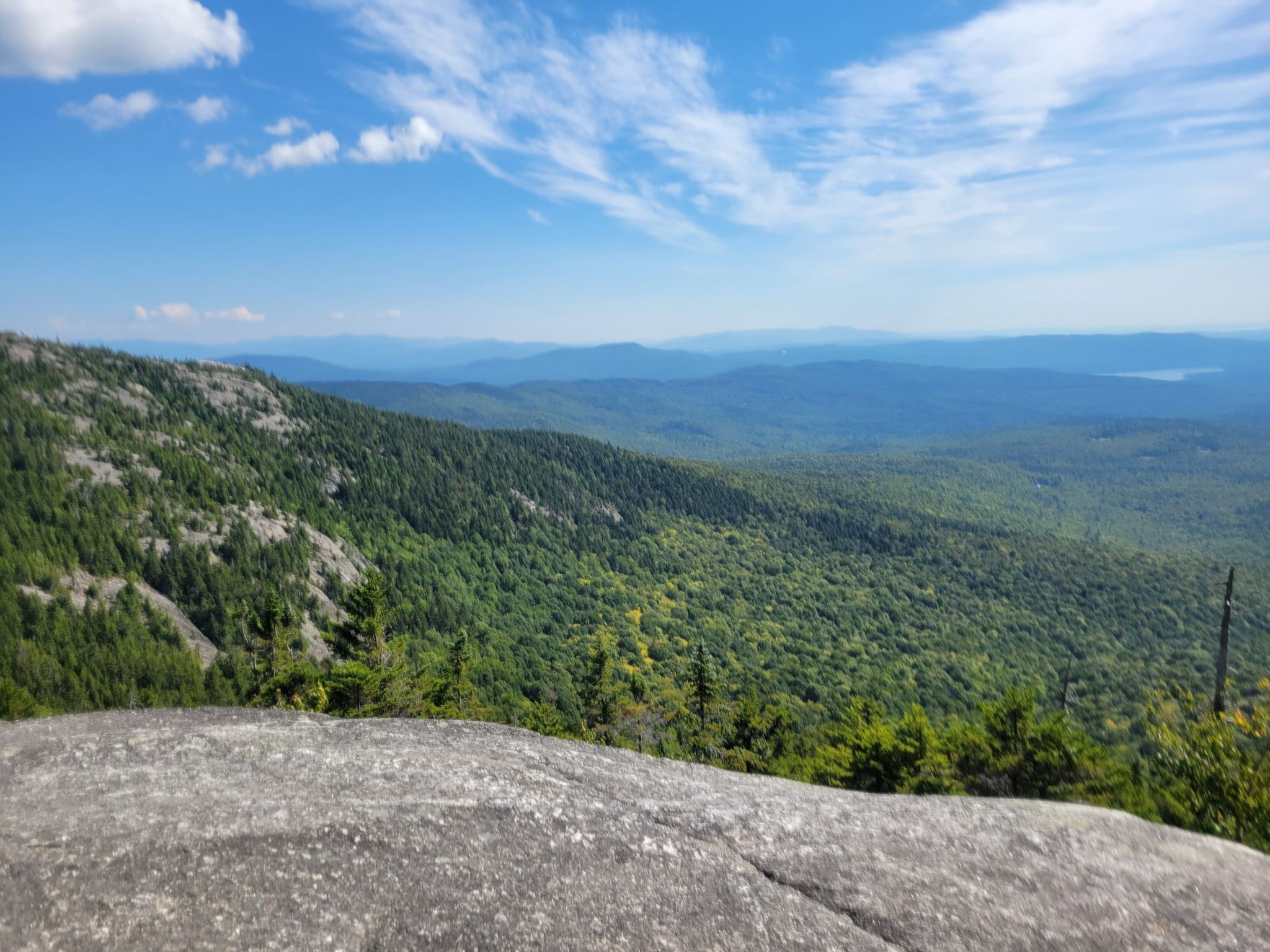 Vast landscape of green forested mountains stretching to the horizon on a clear day. - Mount Cardigan via the Holt Trail Loop